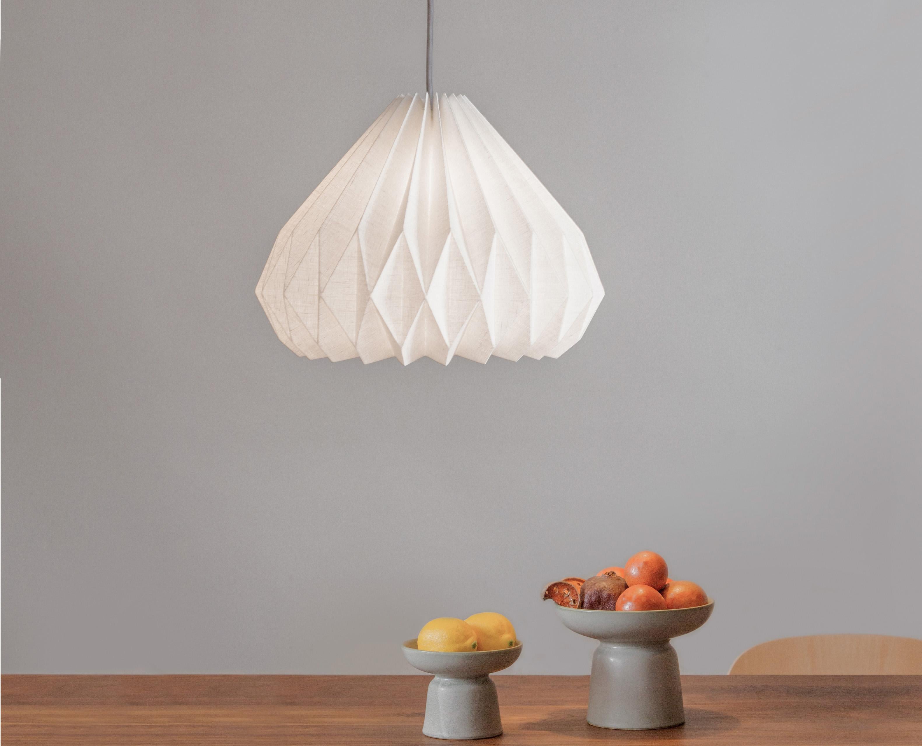 This modern-style pendant light will add an interesting and functional work of art to your interior.
Made of hand-folded laminated line fabric, the pendant shade provides soft ambient lighting while maintaining a delicate and refined aesthetic with