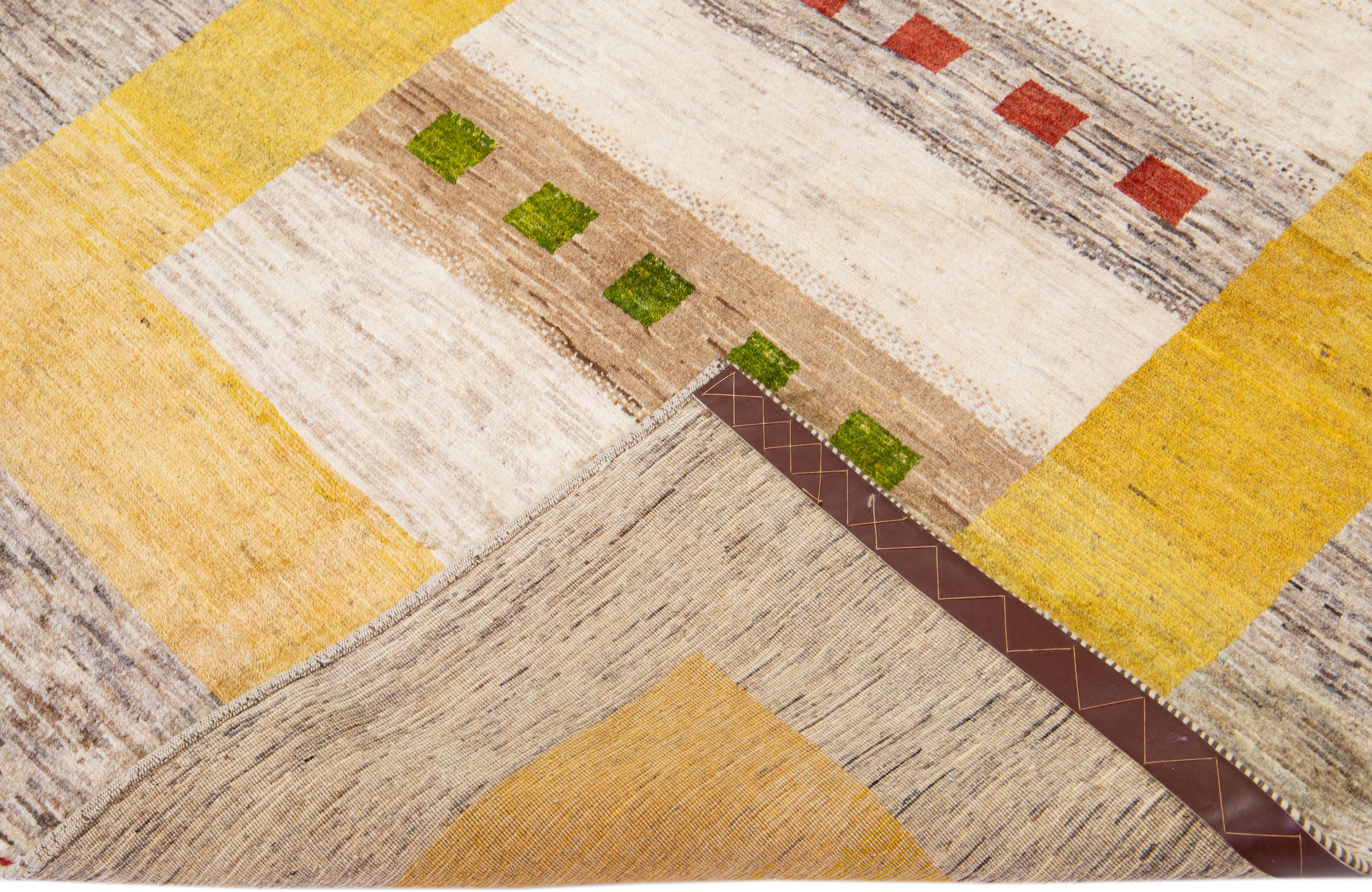Beautiful modern Gabbeh hand-knotted wool rug with a brown and yellow field. This Persian rug has green, red, and beige accents in a gorgeous geometric design.

This rug measures: 4'9