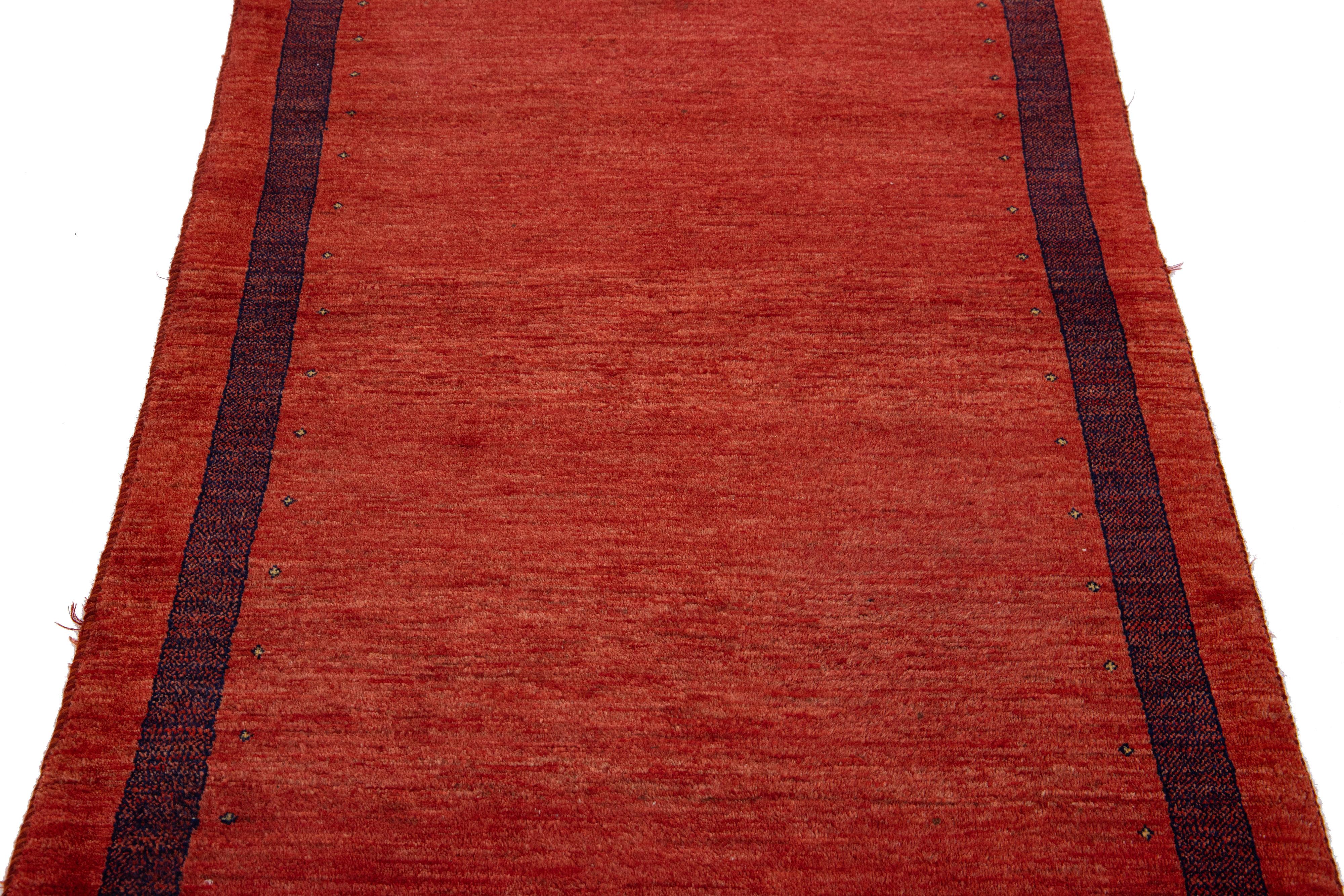 Magnifique tapis moderne en laine tissée à la main de style Gabbeh avec un champ de couleur rouge. Ce tapis persan présente un superbe design minimaliste avec des accents noirs.

Ce tapis mesure : 3'6