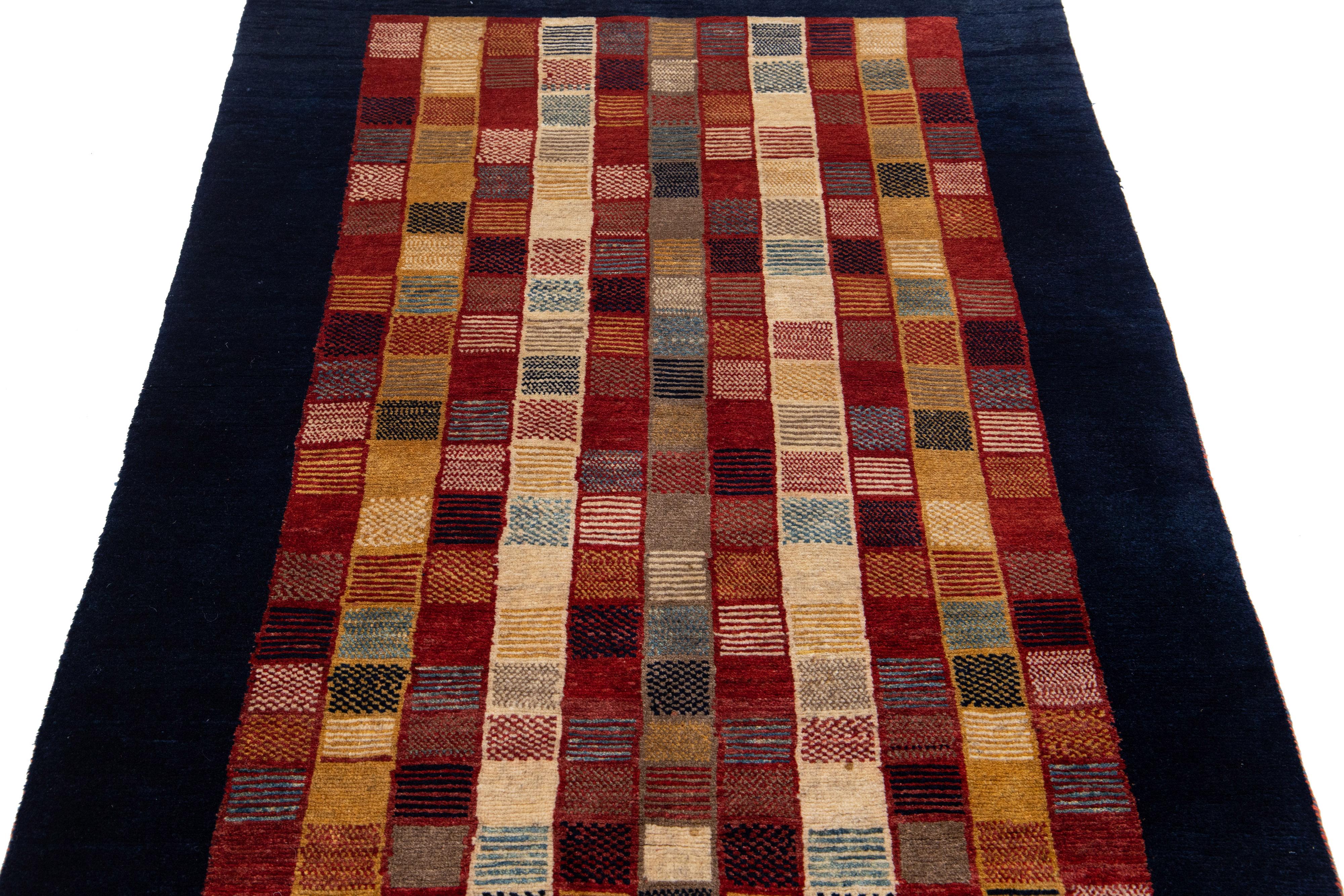 Beautiful modern Gabbeh-style hand-woven wool rug with a red color field. This Persian rug has a gorgeously minimalist design with a navy blue frame and multicolor accents.

This rug measures: 3'7