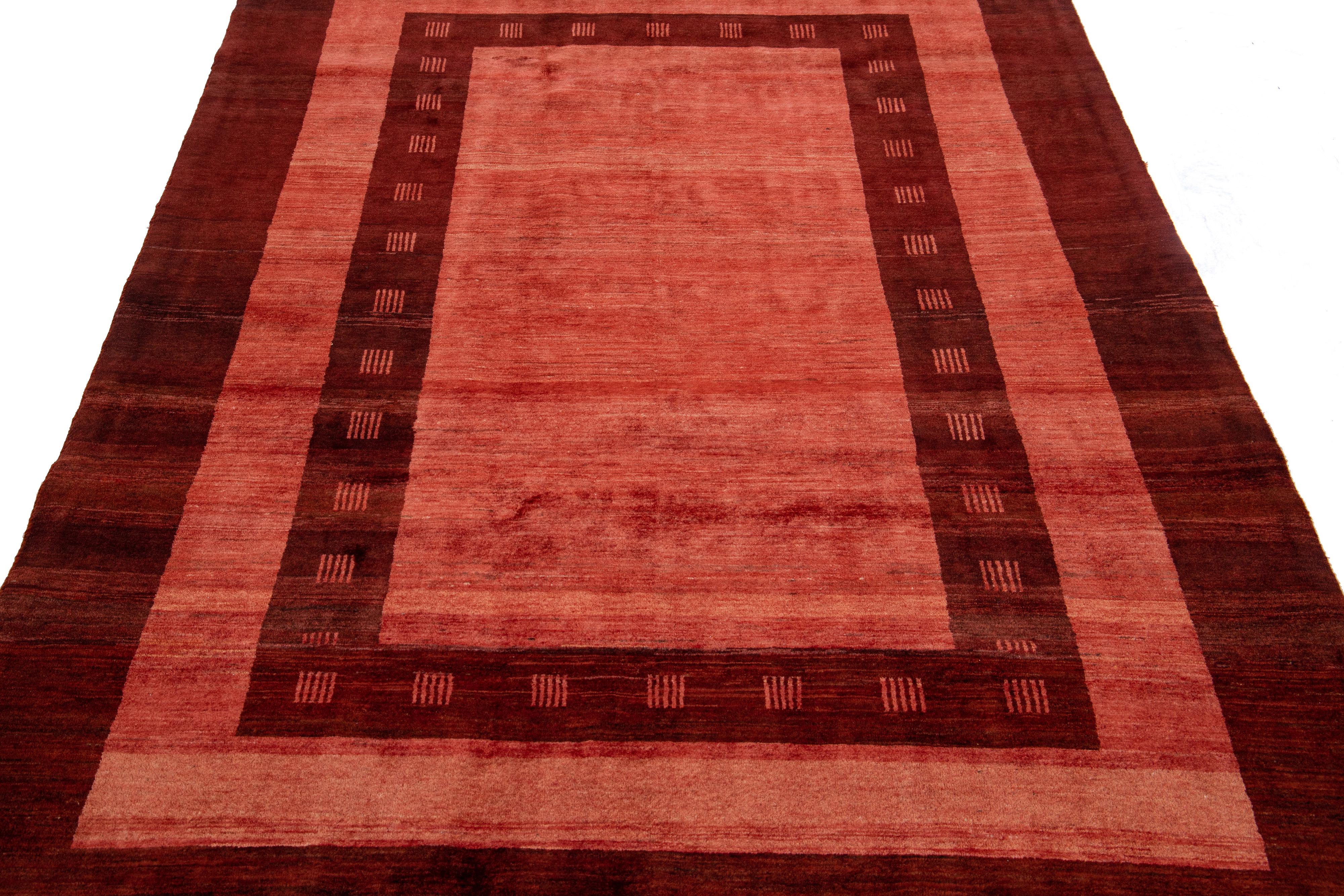 Beautiful modern Gabbeh-style hand-woven wool rug with a red color field. This Persian rug has a gorgeously minimalist design with burgundy accents.

This rug measures: 5'7