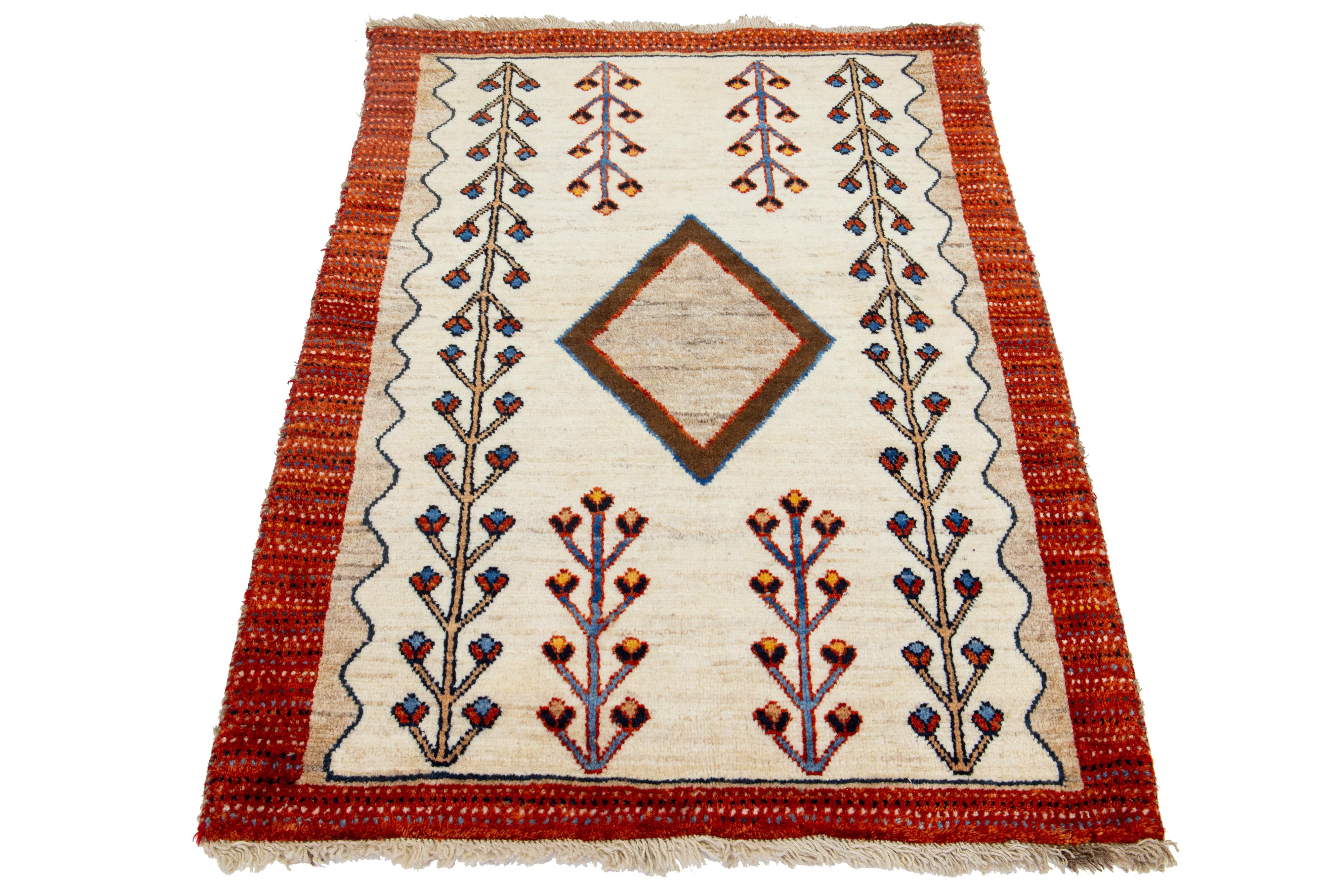 Dieser moderne Gabbeh-Teppich ist handgeknüpft und weist ein zeitgenössisches geometrisches Muster auf. Der beigefarbene Sockel wird durch rostfarbene, braune und blaue Details akzentuiert.

Dieser Teppich misst 3'3