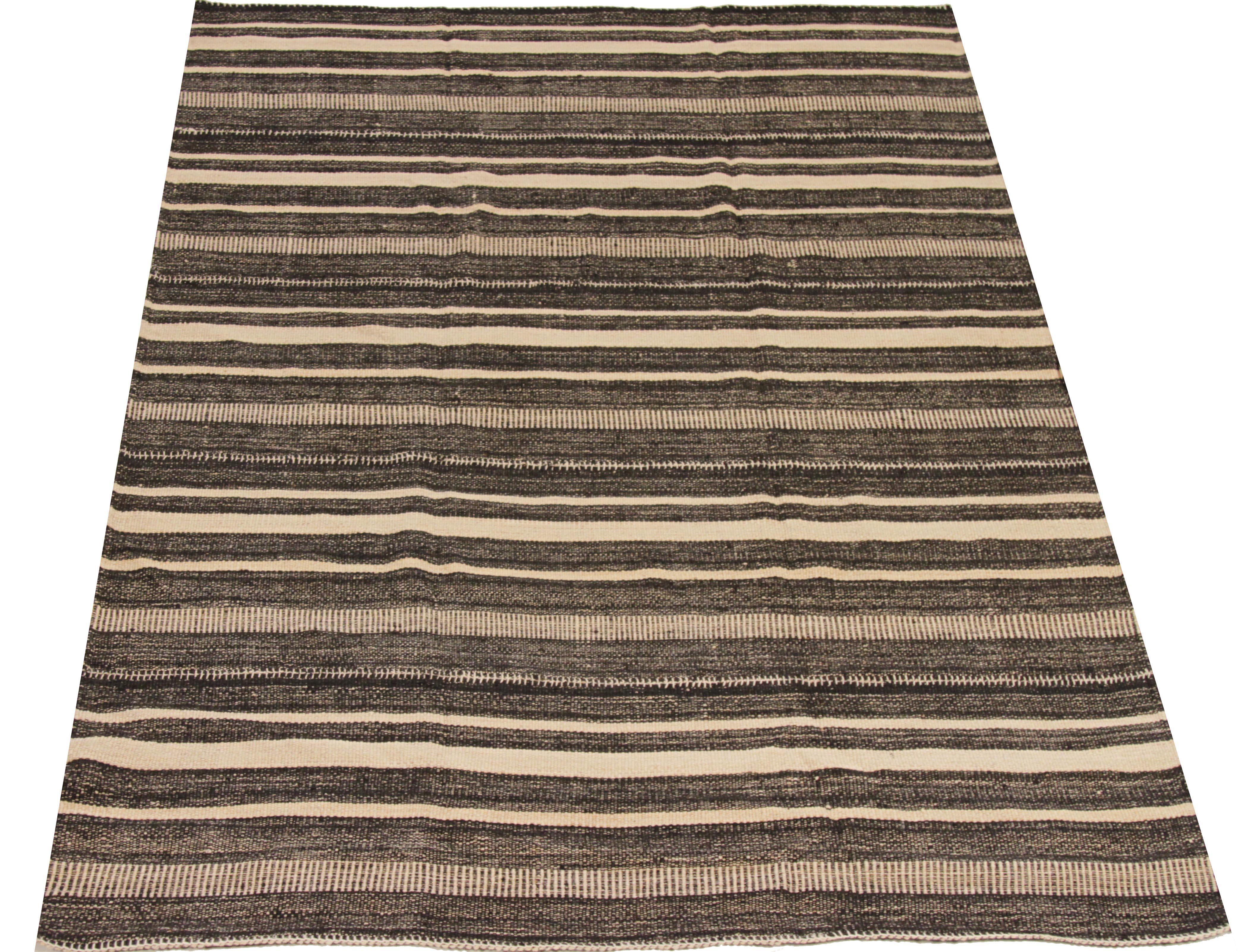 Persian rug handwoven from the finest sheep’s wool and colored with all-natural vegetable dyes that are safe for humans and pets. It’s a traditional Kilim flat-weave design featuring an exquisite ivory field with alternating black and brown stripes.