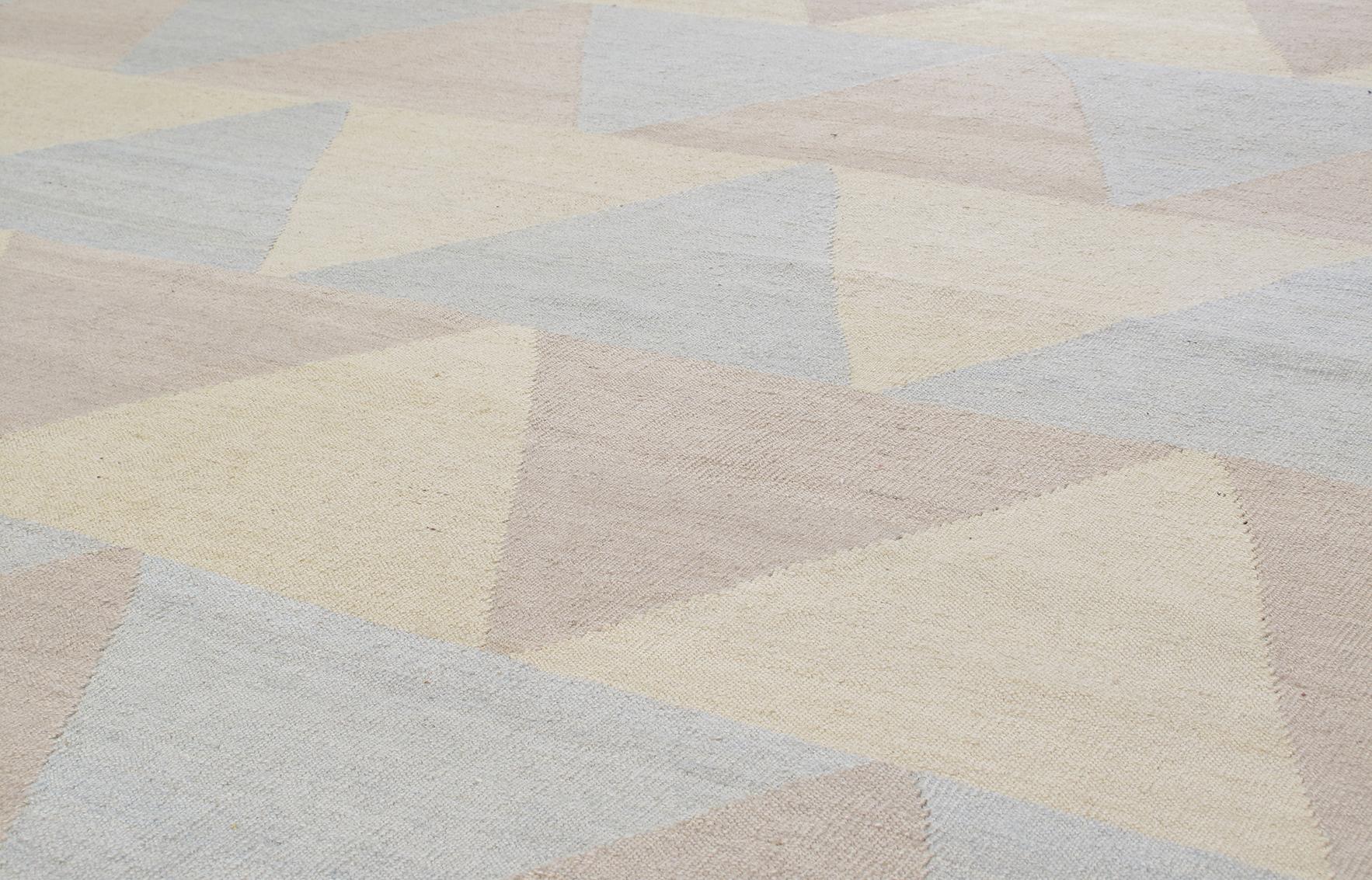 This modern flat-weave rug is made with handspun (wool or wool and cotton) and natural dyes. It features chevron-like design in soft, pastel color tones of sand, blue, and yellow. It is inspired by the vintage kilims that are native to the Shiraz