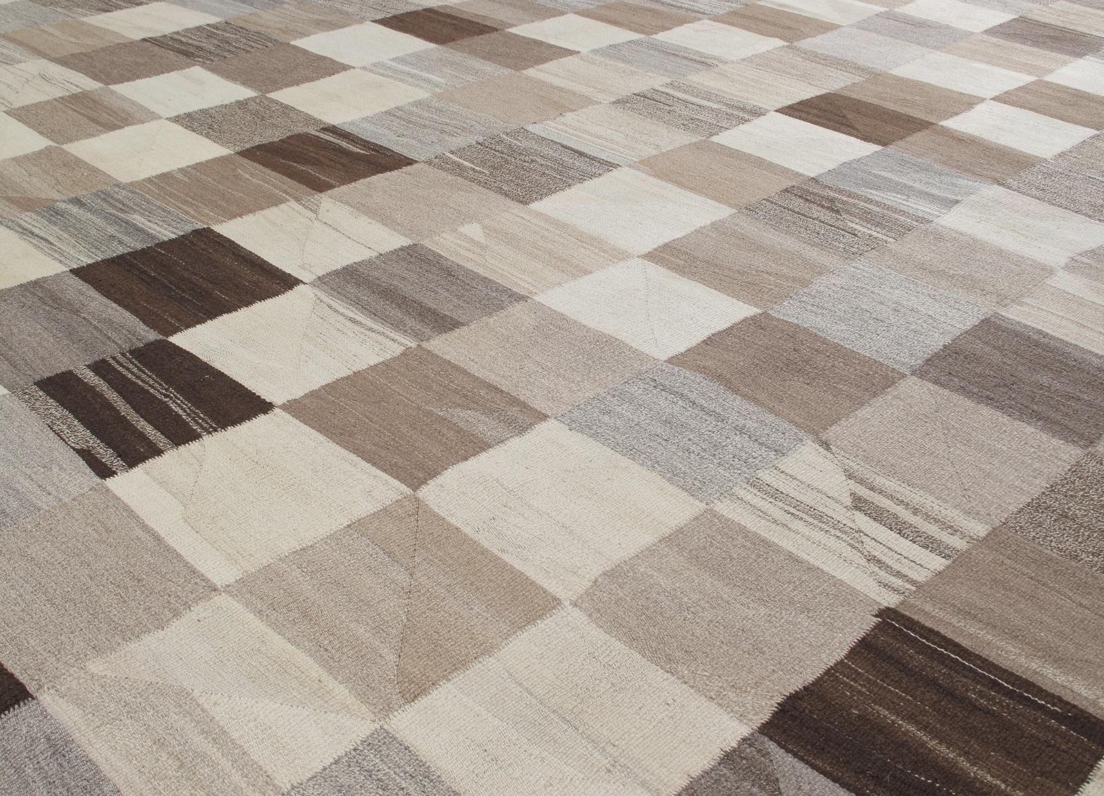 This modern flat-weave rug is made with 100% handspun, non-dyed Persian wool. It features a checkered pattern all made of undyed wool ranging from beige, browns, taupes, and greys. It is inspired by the vintage Kilim that are native to the Shiraz