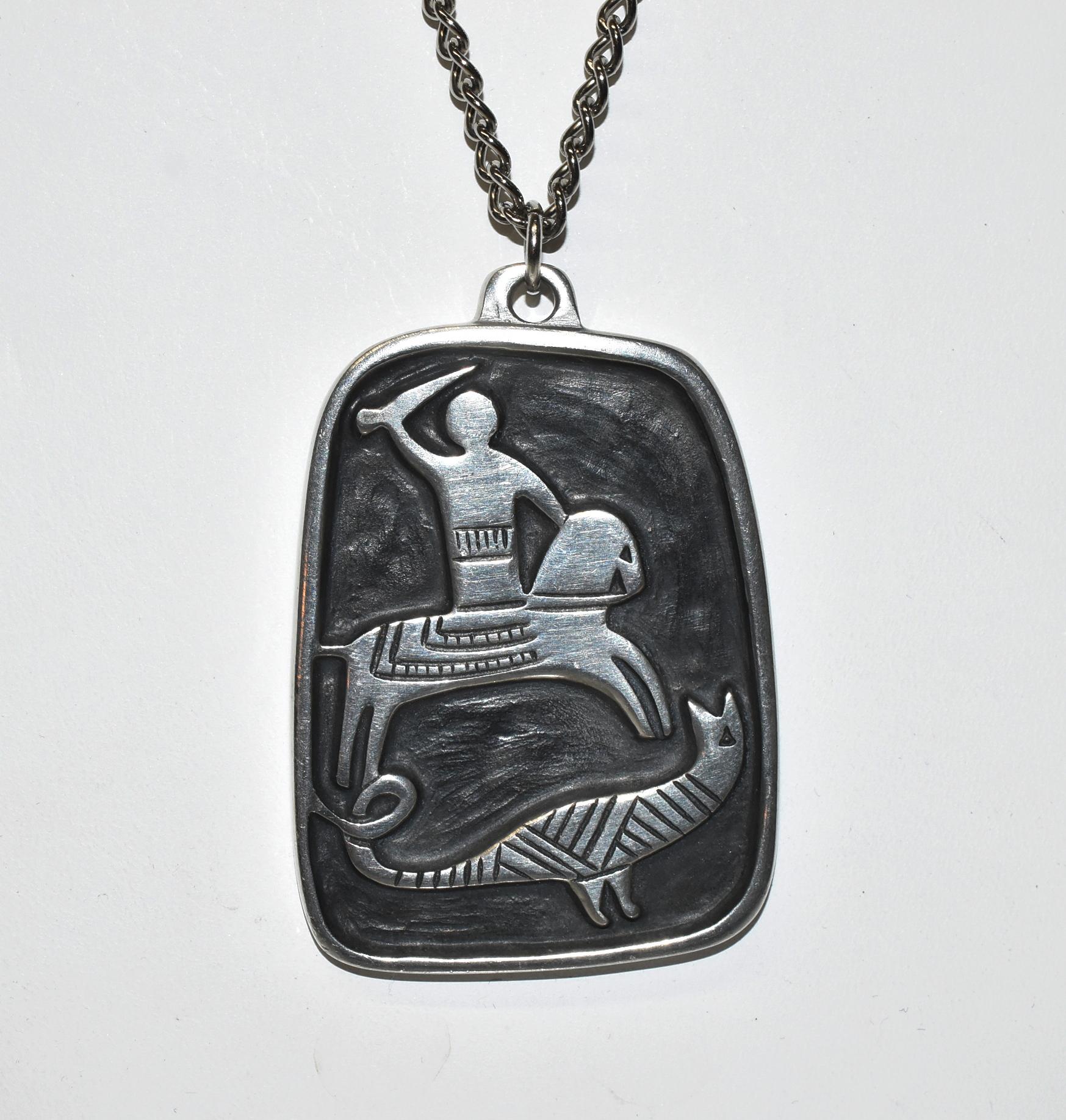 Modern pewter necklace by R. Landerholm. Depicts St. George slaying a dragon. Signed on the back with a crown hallmark. Very nice condition. Dimensions: 1.5