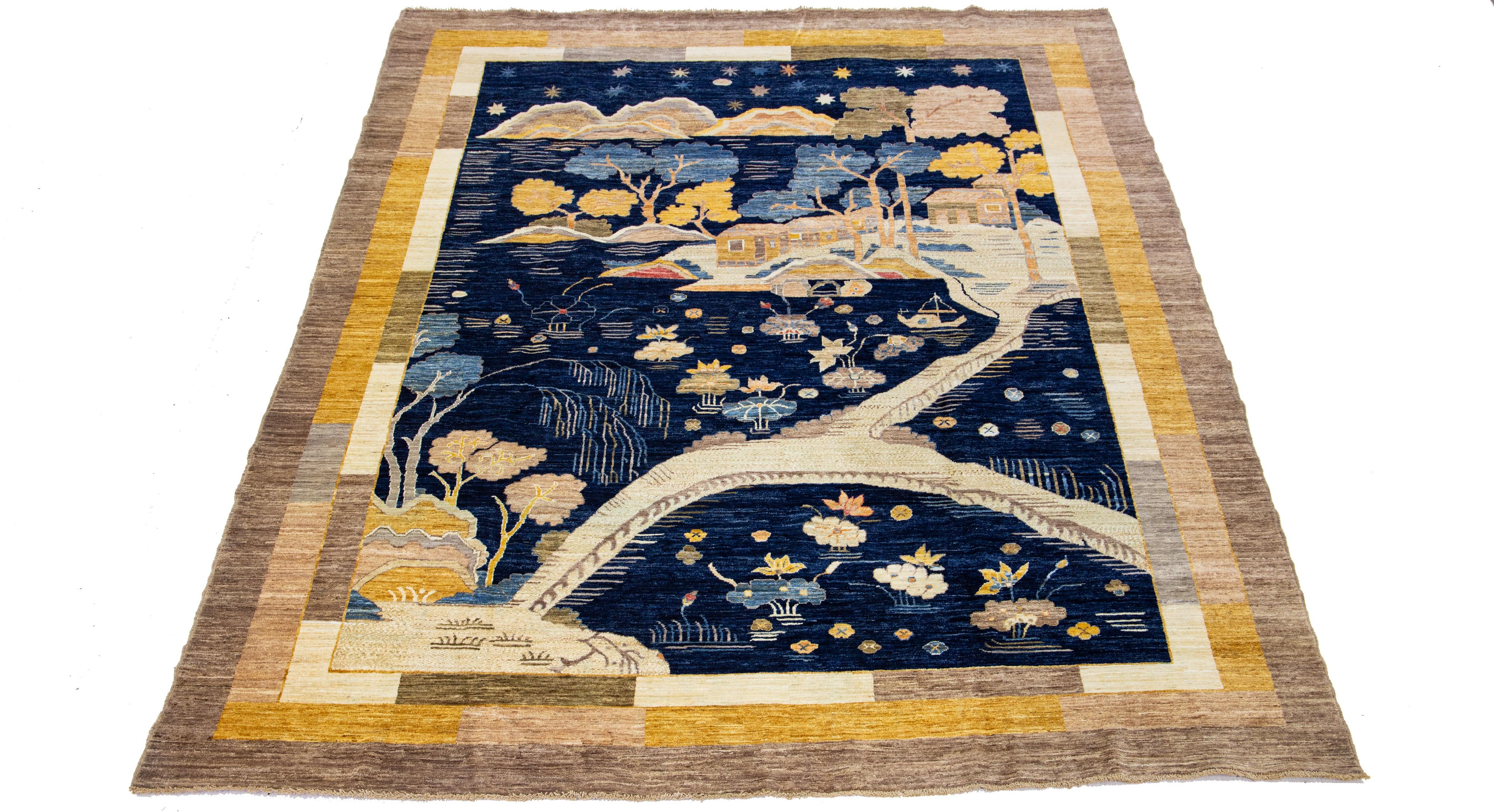 This hand-knotted wool rug showcases an exquisite Modern Art Deco design with a rich navy blue field accentuated by a broad goldenrod and brown frame. The intricate Chinese-style elements are beautifully depicted throughout the rug, embellished with