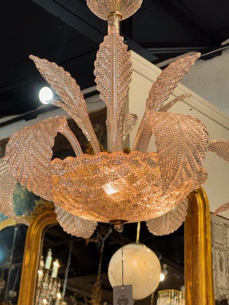 Esta moderna araña de cristal de Murano rosa presenta un diseño único en forma de hoja, que añade un toque de elegancia y sofisticación a cualquier espacio. El suave color rosa añade un sutil toque de color, mientras que el moderno diseño de la