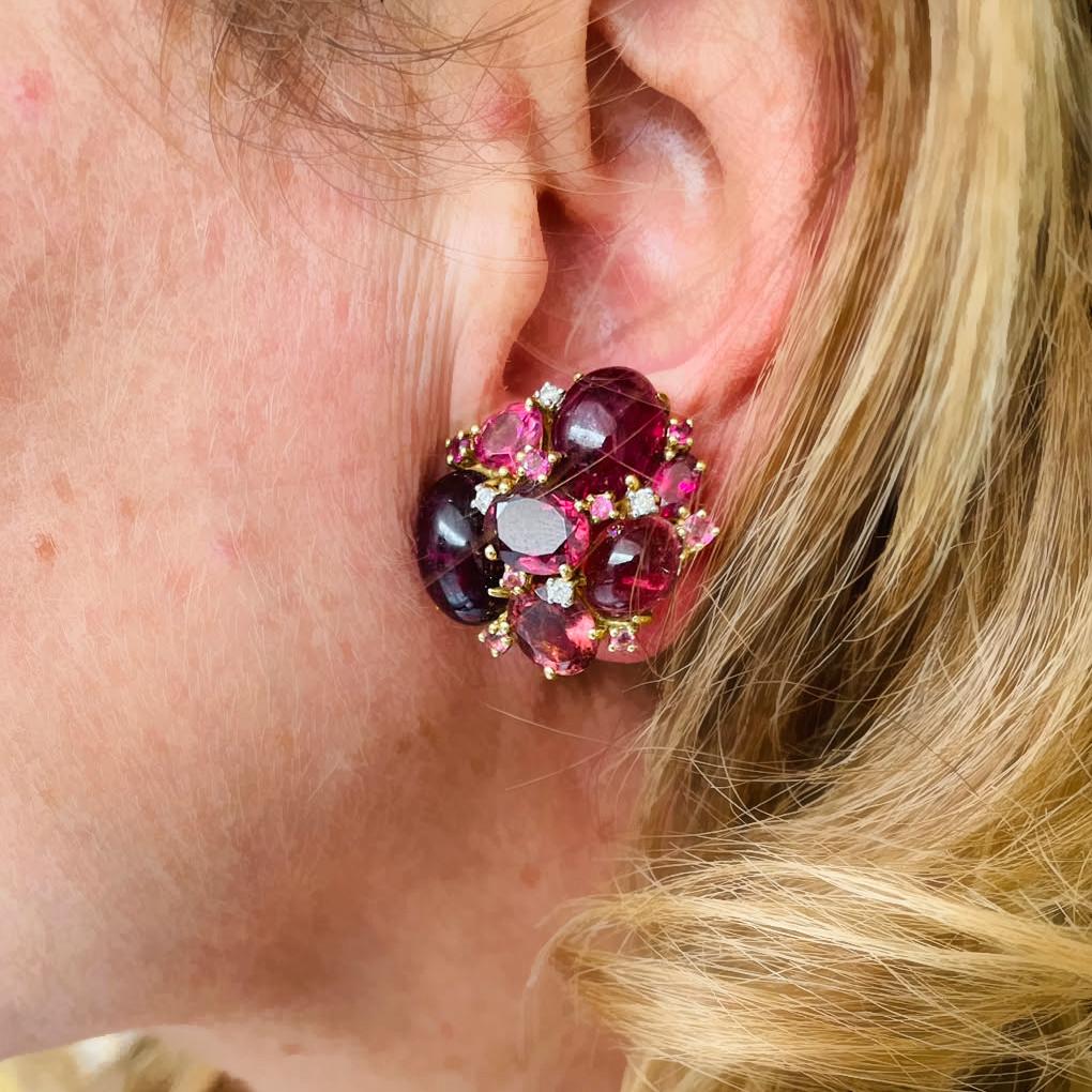 A pair of modern pink tourmaline cluster earrings, set with mixed fancy cuts of faceted and cabochon pink tourmaline and round brilliant-cut diamonds, with posts and clip fittings, mounted in yellow gold, with a given total weight of 43.53 carats of