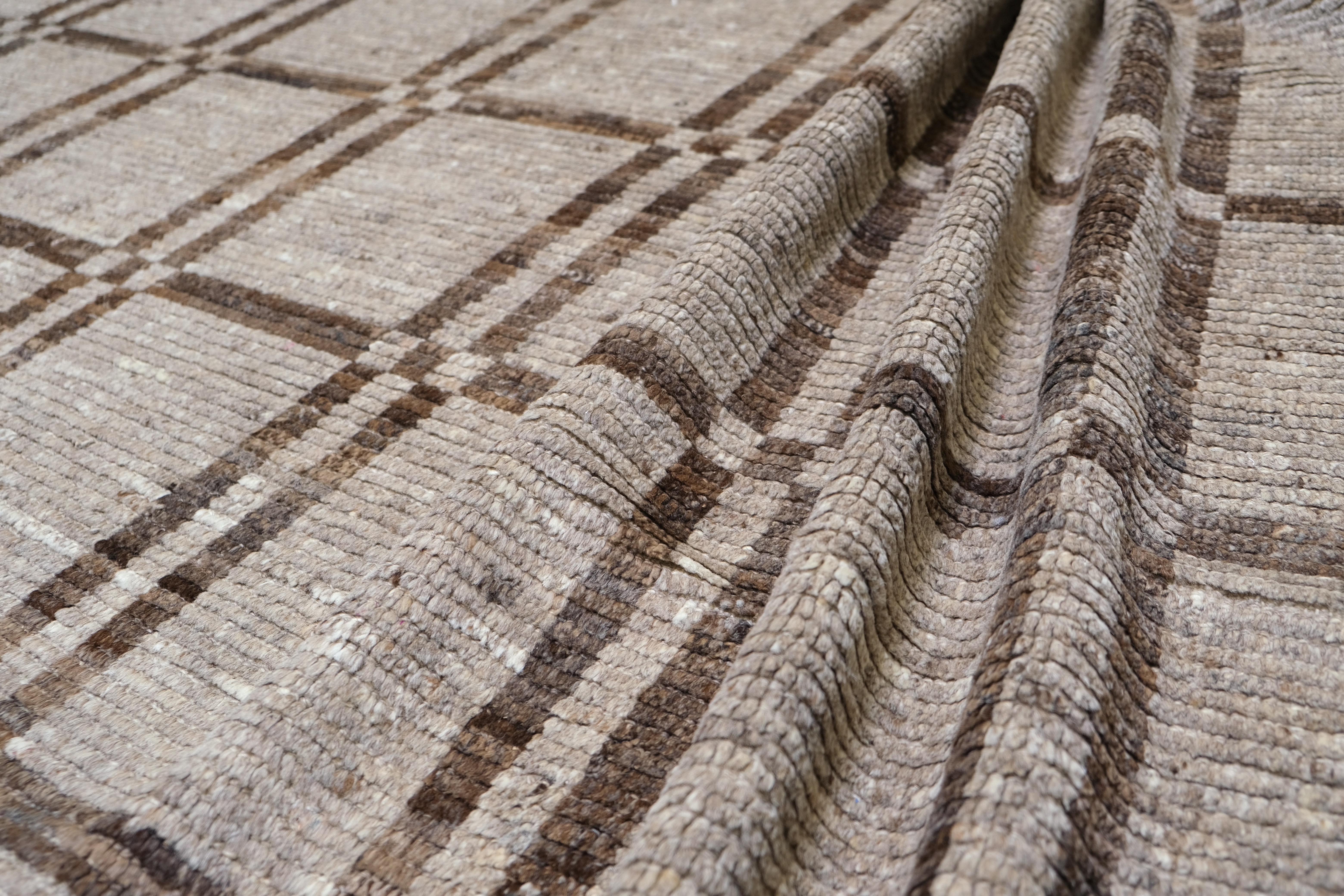 Ce tapis en laine nouée à la main en Afghanistan présente un motif écossais intemporel qui allie tradition et élégance discrète. Les tons harmonieux de beige, d'ivoire et de brun terreux créent une palette neutre qui complète une variété de styles