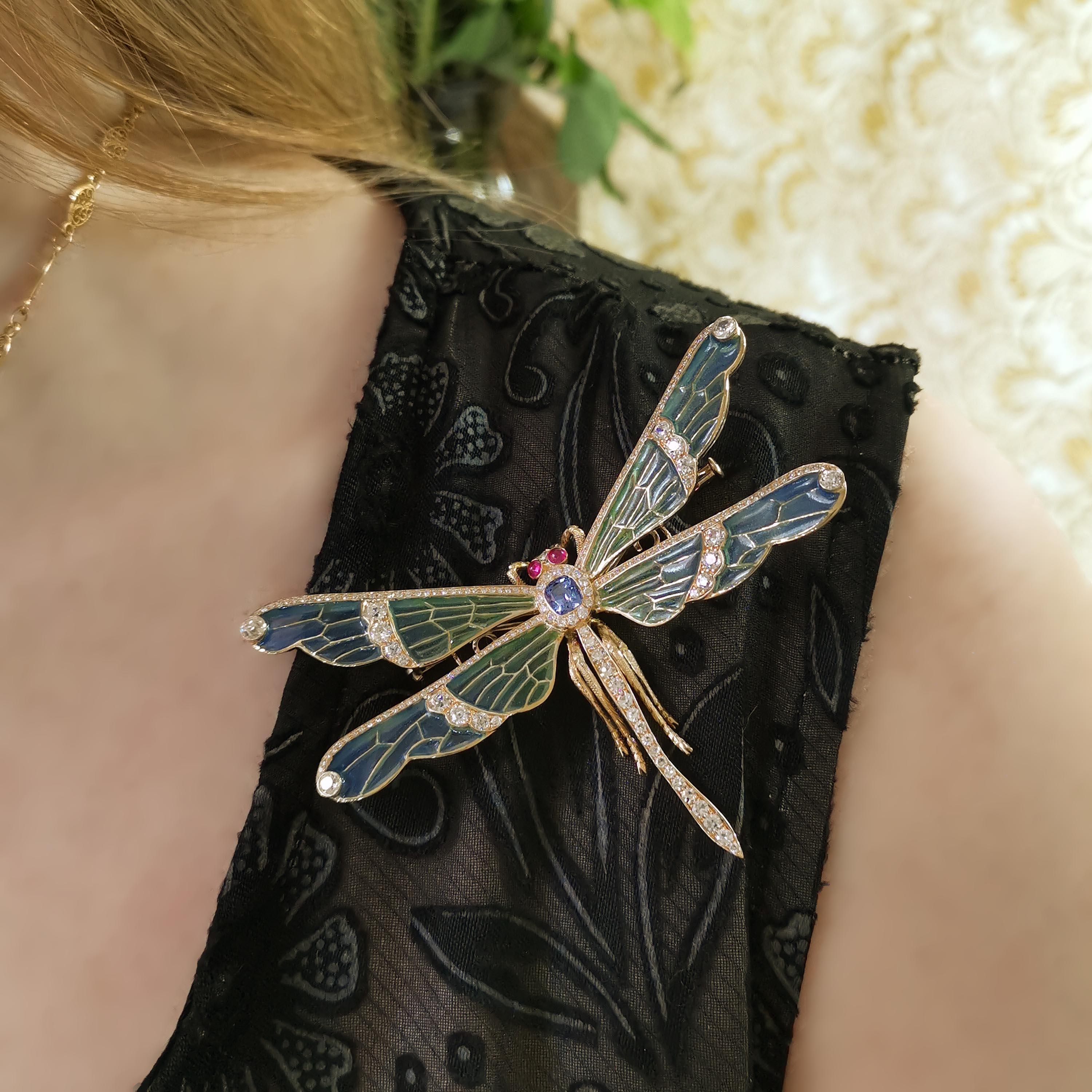 Un moderno broche libélula engastado, con un zafiro facetado en forma de cojín, que pesa  0,86 quilates, engastada en el tórax, con diamantes redondos talla brillante alrededor, con alas de esmalte plique à jour azul a verde, engastadas con