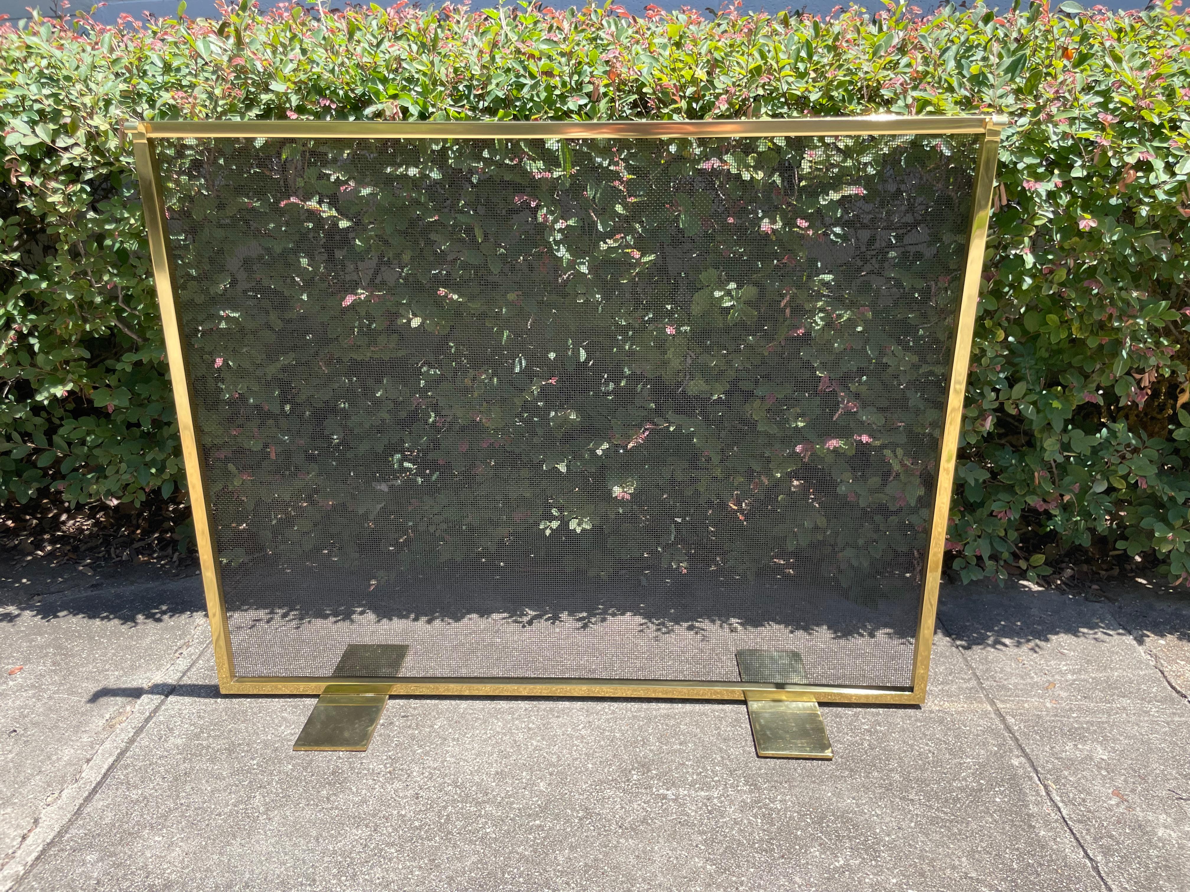 This elegant brass fireplace screen features a rectilinear frame in polished and un-lacquered brass with a blackened iron mesh backing. With its modern form and clean lines, this piece would be a fabulous addition to any style of interior from