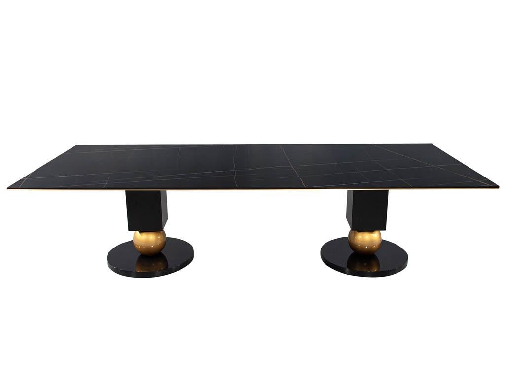 Modern Porcelain Dining Table with Brass Accents. Large 10ft porcelain slab in black with beautiful copper and grey veining. Completed with brass trim accents running around the perimeter of the tabletop. 2 unique geometric pedestals keep the table