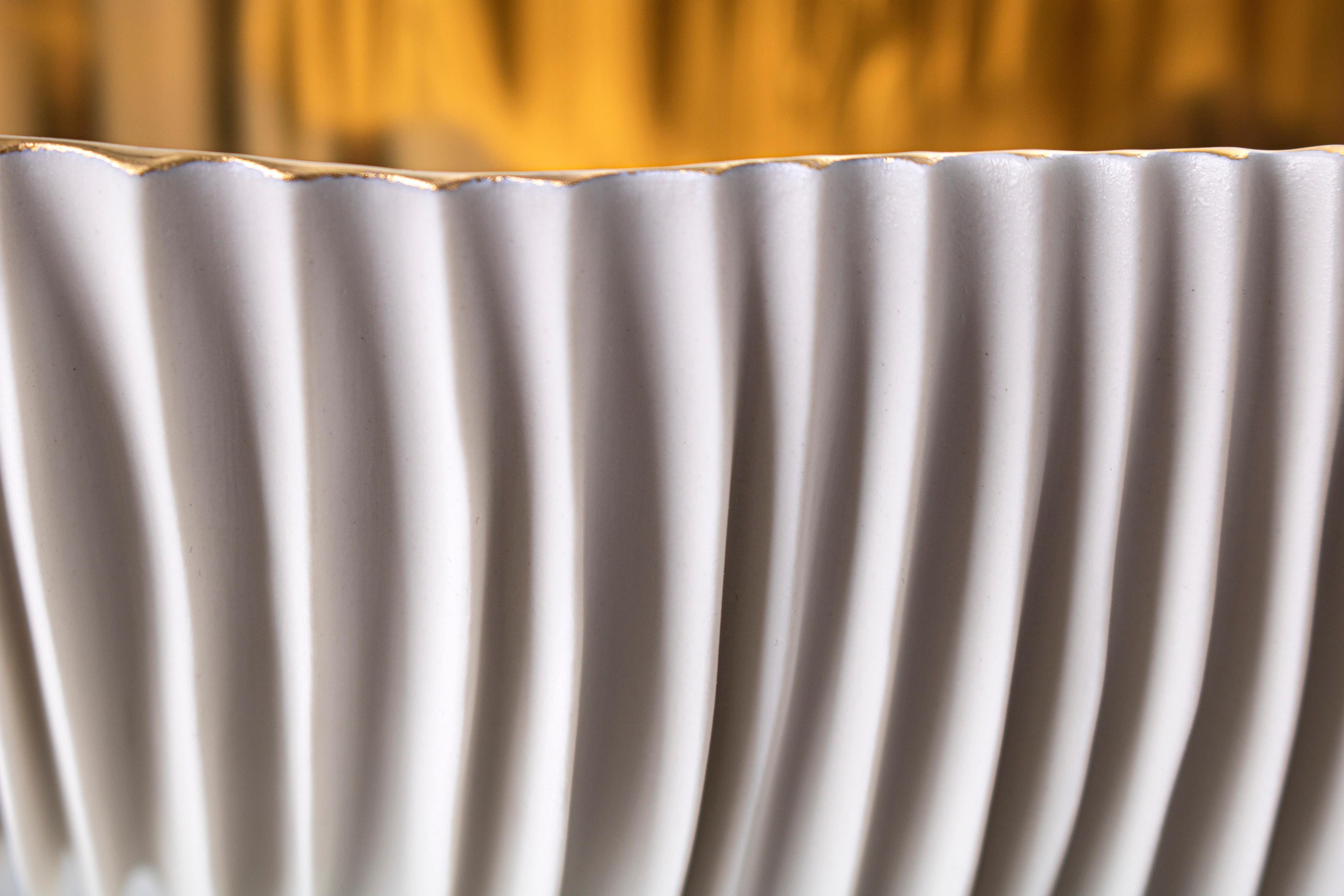 The eye lose itself amid a thousand channels in a succession of plans chasing the dense lamellar structure. Snow-white porcelain bowl from which emerge the spark of precious gold 23k, applied by hand and fixed through an additional meticulous firing