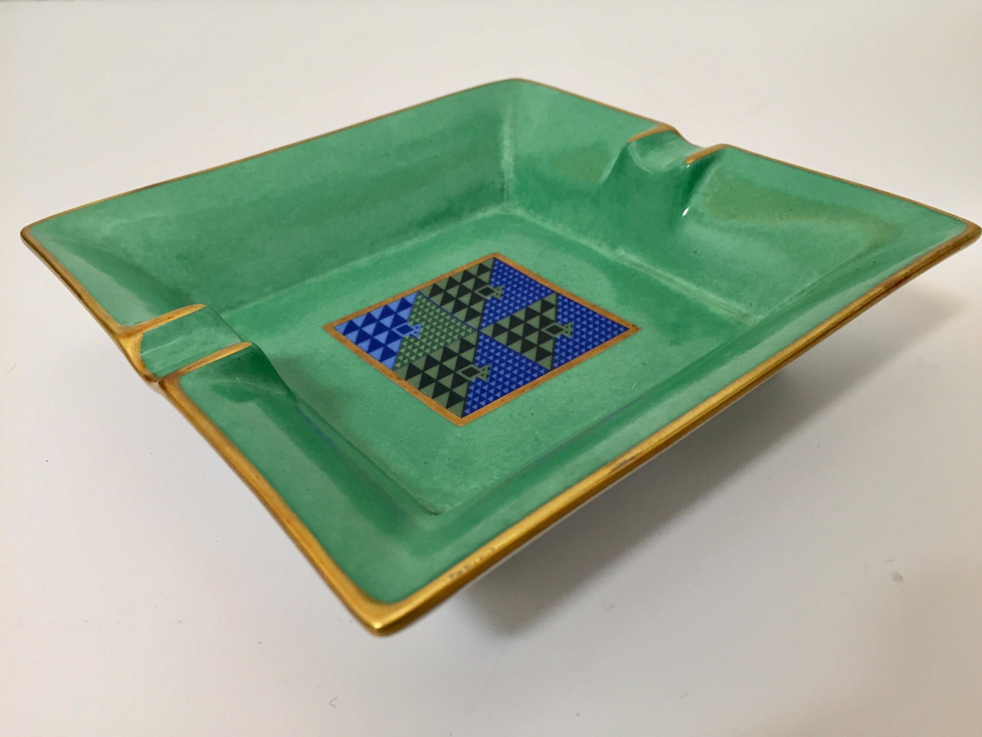 Modern Bauhaus porcelain square green and gold ashtray with a modernist abstract blue design in the middle.
Use it as an ashtray, vide poche or for decorative bowl.
Stamped Limoges, Porcelain, France.
Bauhaus style with Post Modern design.
  