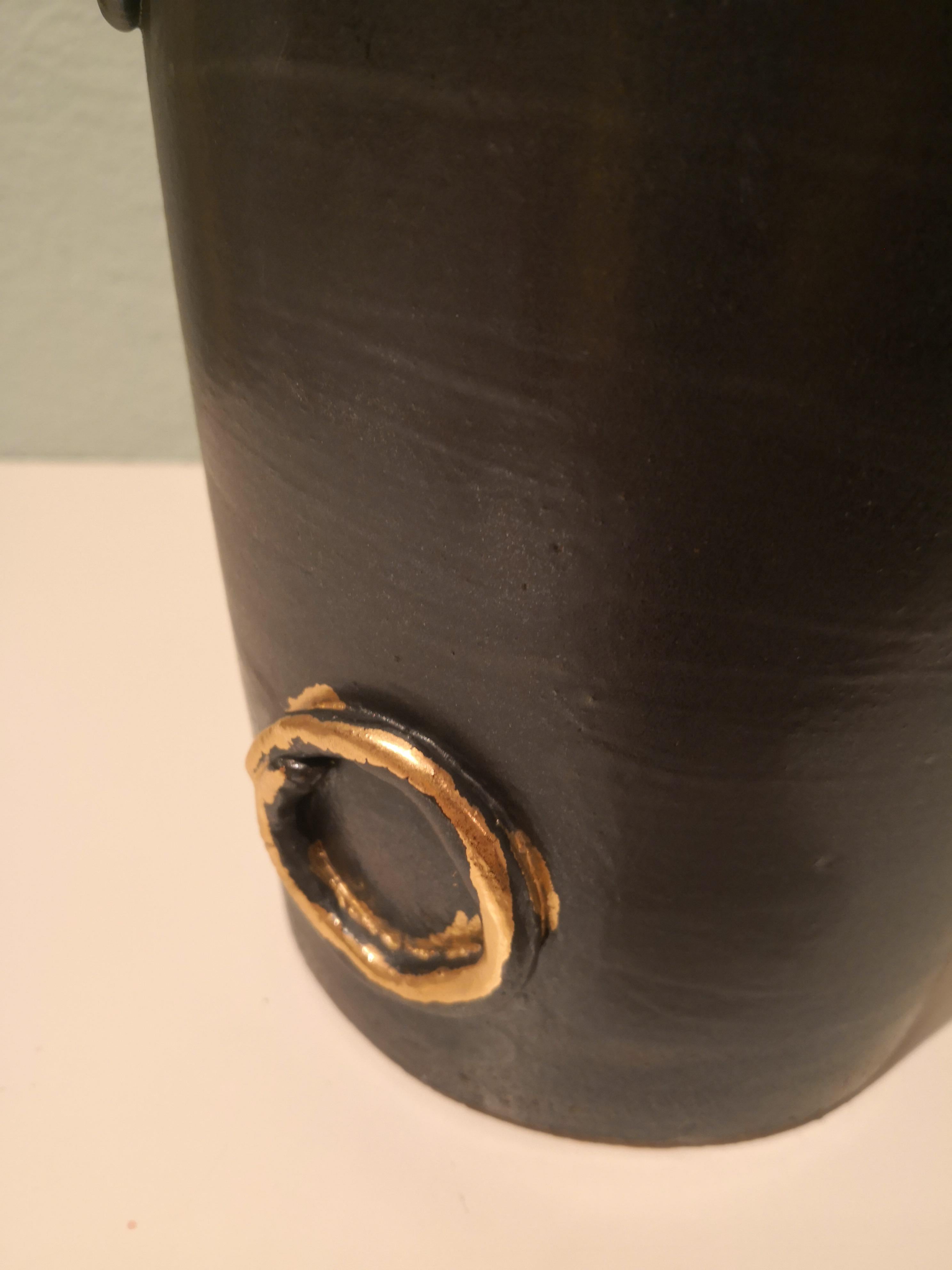 Handmade pottery vase in black earthenware and decorated with handformed golden details. Formed by hand in a strong straight form. Rimed with a gold line. In the bottom signed by the artist. Handmade for Sofina Boutique Kitzbühel. Unique piece in