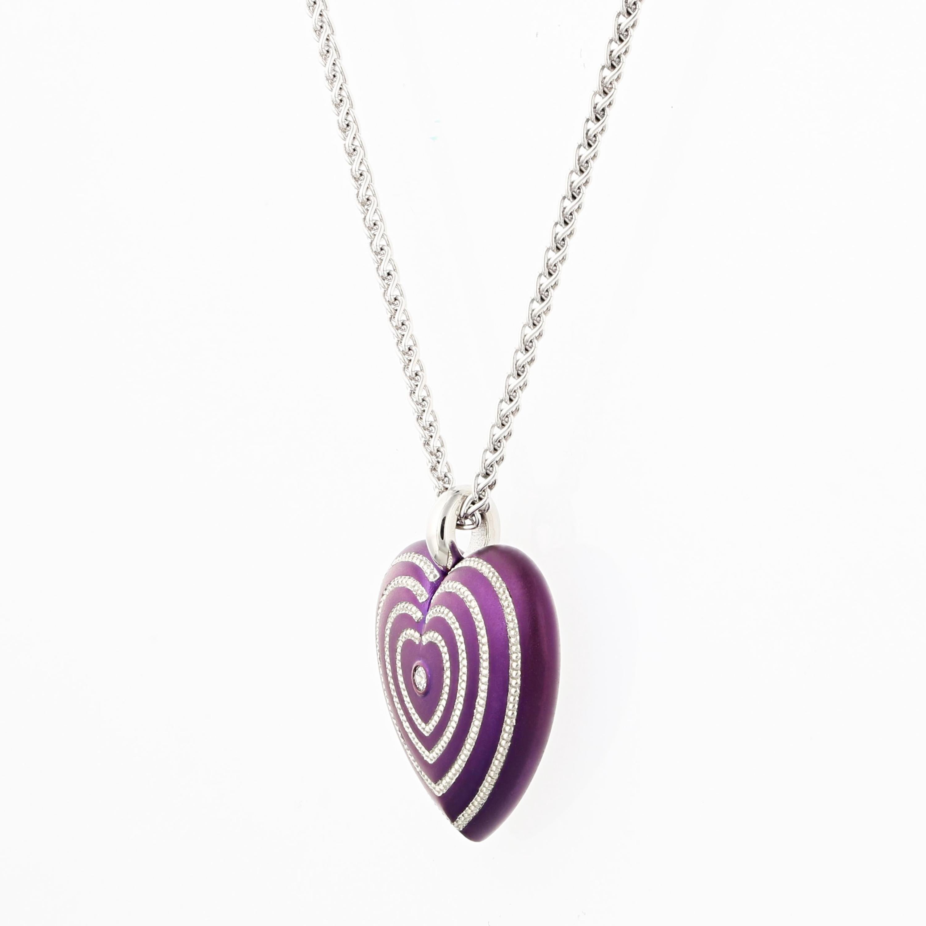 Heart pendant in purple steel with concentric lines of pure platinum hand engraved shaped inlay. A single .03 ct. round brilliant E/VVS diamond is set in the center. The back has 'LOVE' inscribed around the perimeter. The heart is 3/4