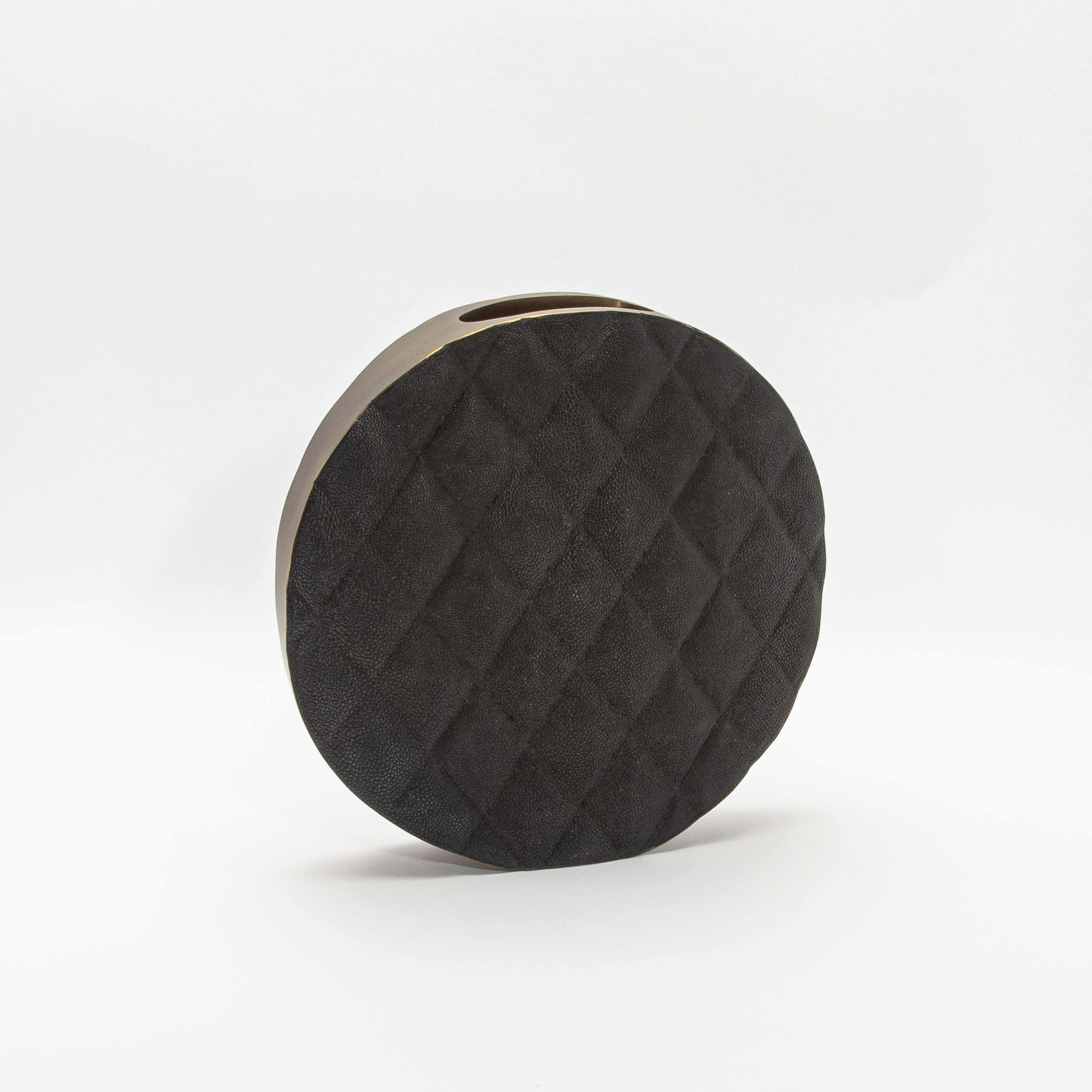 El Jarrón Coco de KIFU Paris es una pieza que combina armoniosamente el lujo moderno con la elegancia atemporal. La superficie del jarrón, fabricada en suntuoso shagreen negro, presenta un llamativo motivo acolchado que destila refinamiento. La