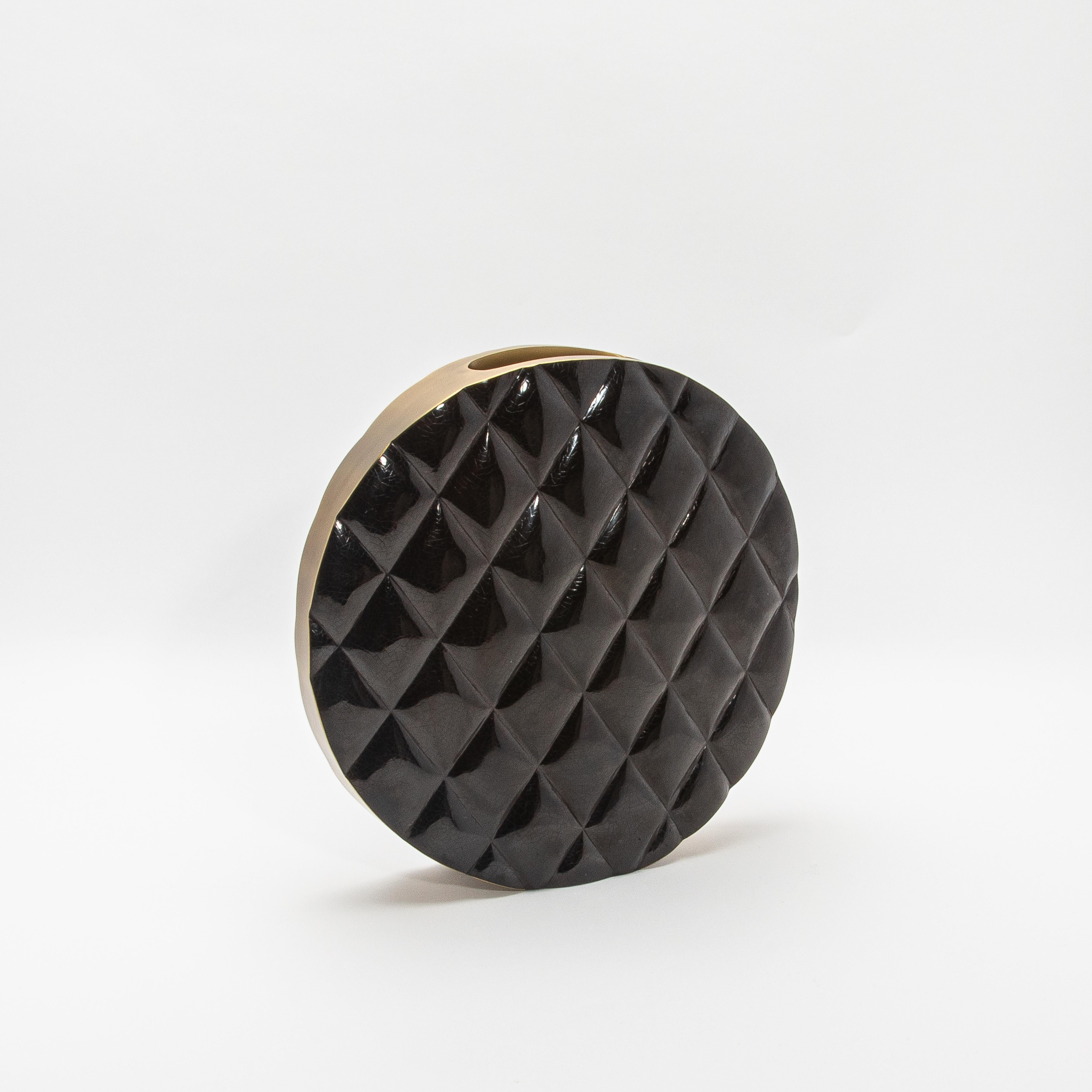 Le vase Coco de Kifu Paris incarne le summum du design sophistiqué avec sa silhouette audacieuse et moderne. Fabriqué en coquillage noir lustré, la surface du vase est méticuleusement matelassée, créant un motif dynamique et tactile qui évoque le
