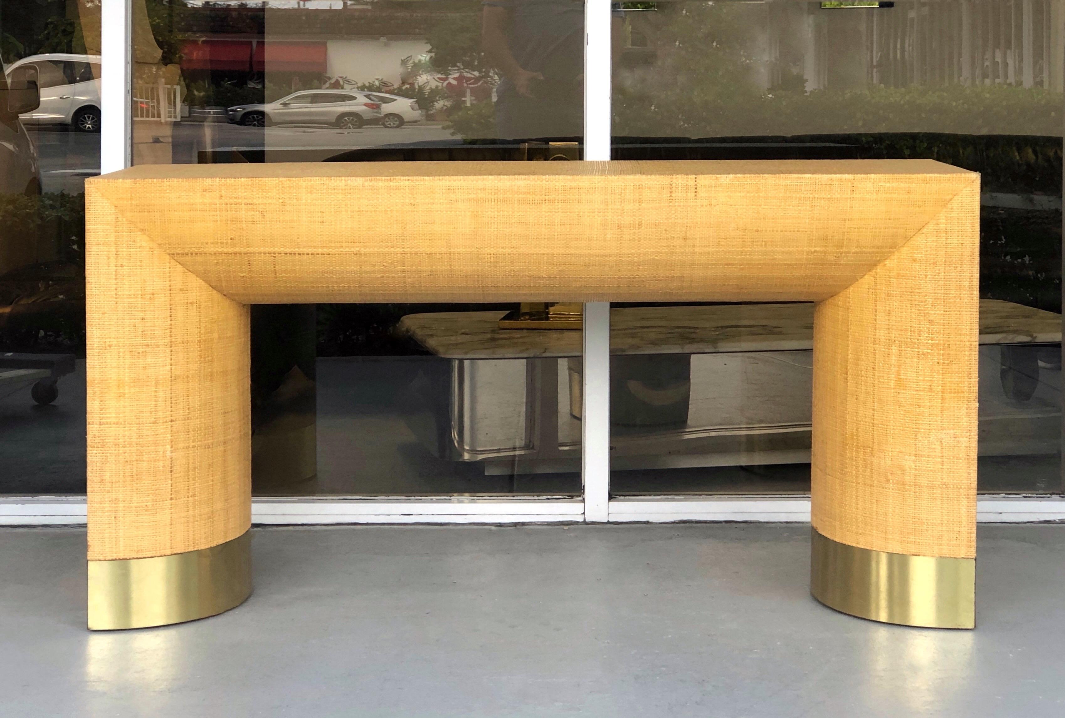 A wonderful console table in the style of Karl Springer. Chunky design with rattan canning covered surfaces, brass accents on bottom of bases.