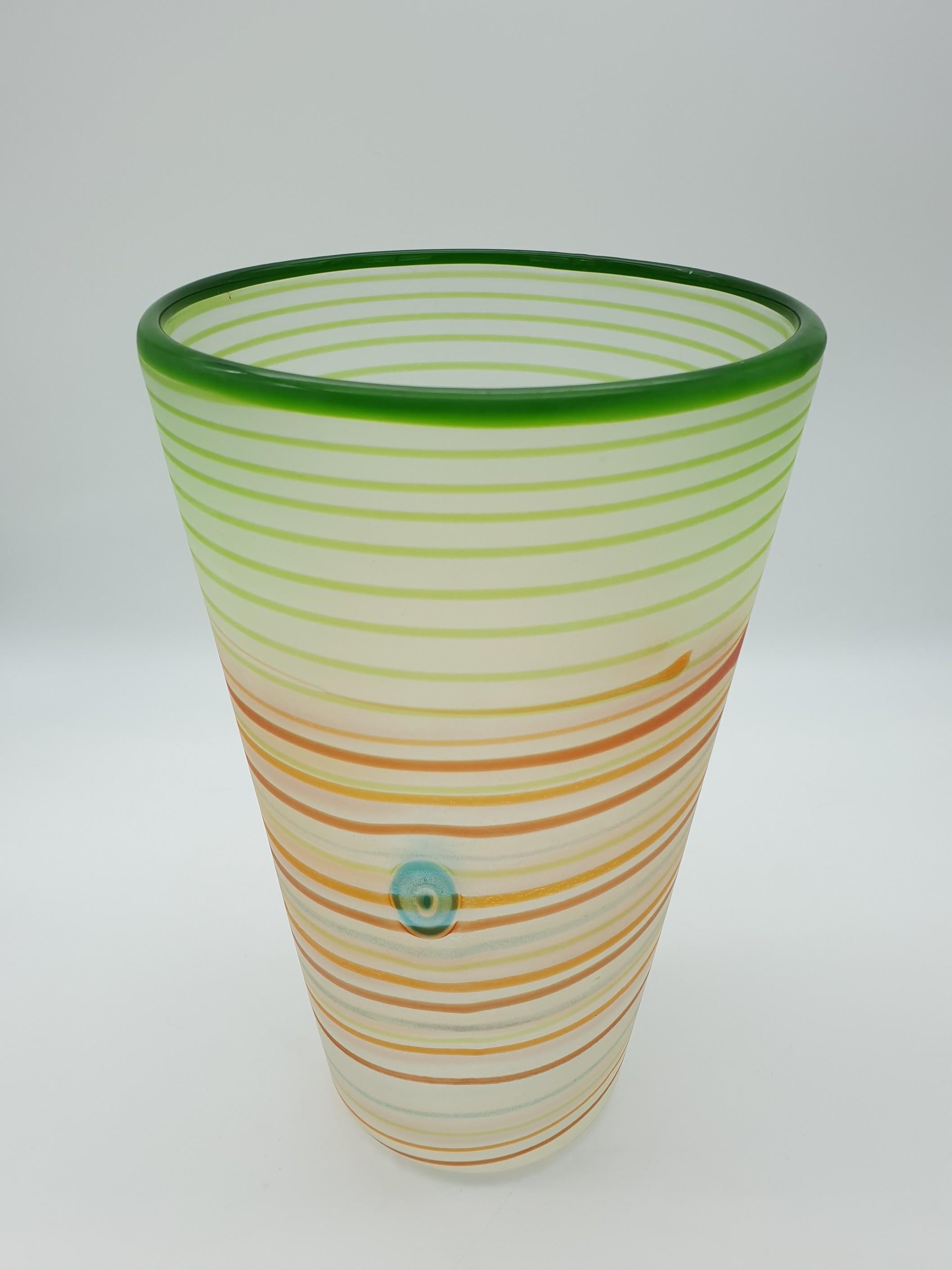 This modern Murano glass vase by Gino Cenedese e Figlio features multi-color glass threads and applied murrine (bull's eye design and flower design). The simple design of the vase enhances the beauty of its bright colors, spyralling from the bottom