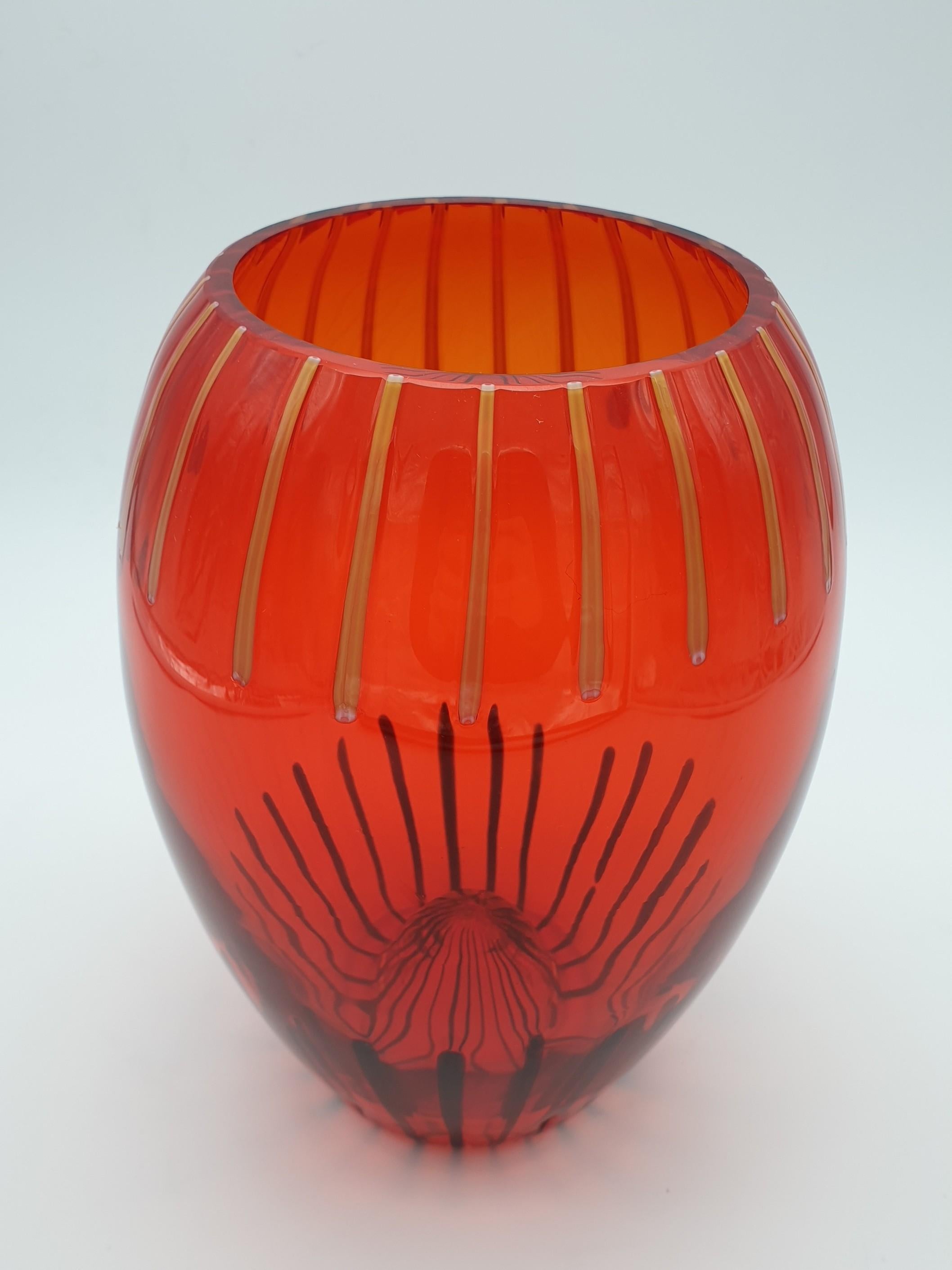 A bongo-drum shaped glass vase, handmade in Murano by Gino Cenedese e Figlio in the late 1990s. Both the bright red color and the contrasting canes on its edges (amber on the top and black on the bottom) recall to memory the flaming sunsets of