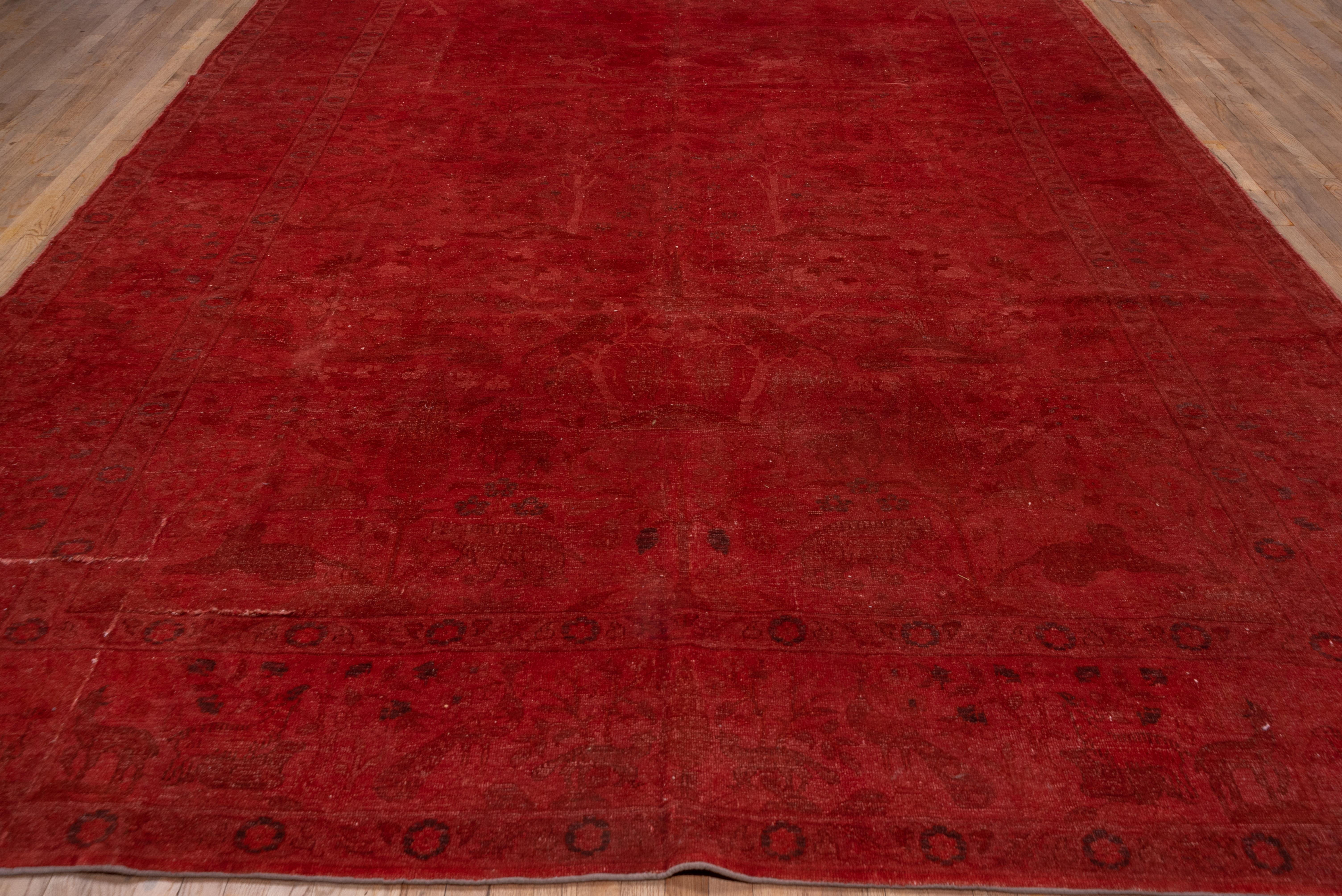 This warm red overdyed Peshawer carpet shows a tone-on-tone pattern of flowering trees and shrubs, within a broad border of cypresses and other trees.
