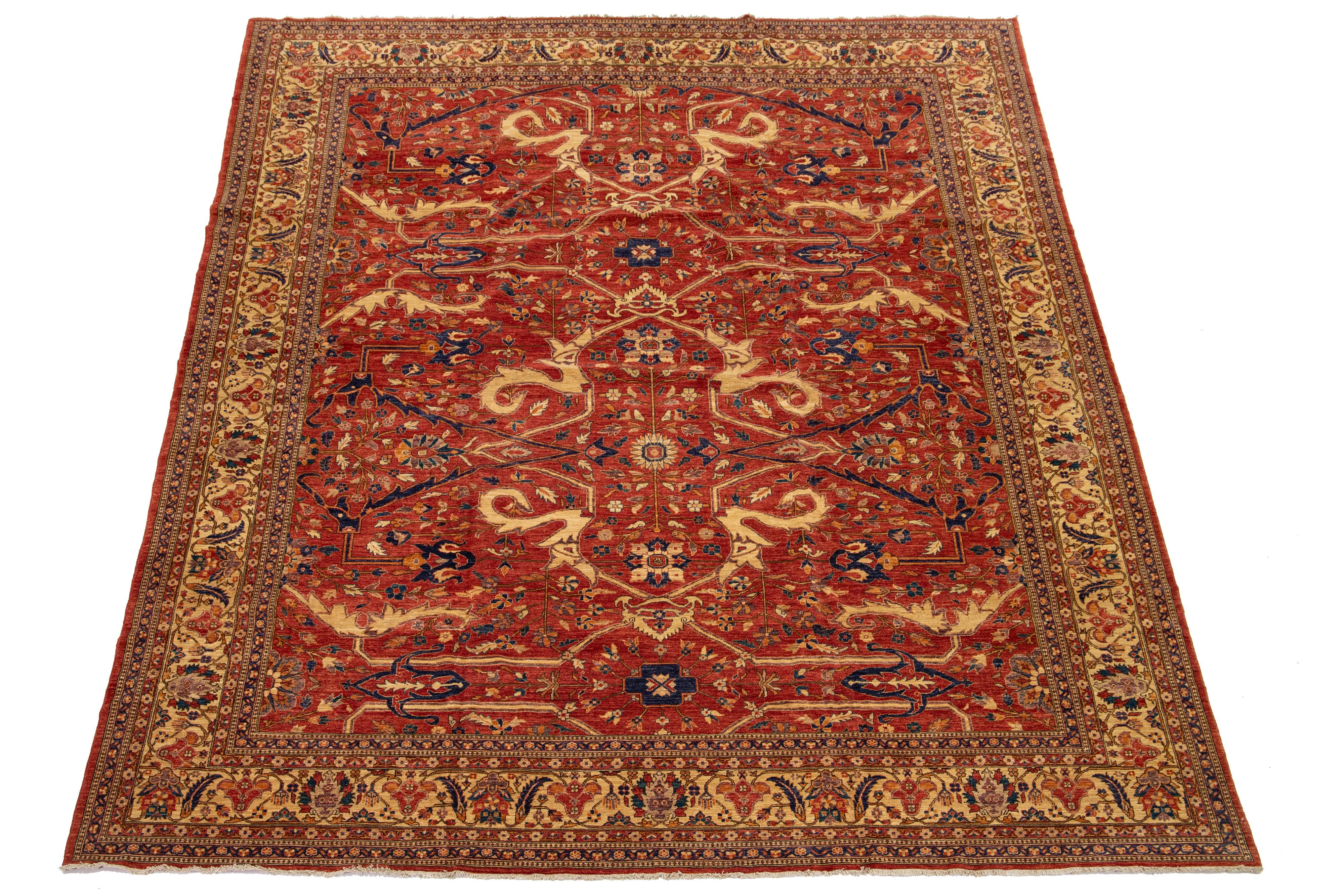 Esta impresionante alfombra del tamaño de una habitación muestra una versión moderna del clásico estilo Serapi, expertamente elaborado con lana de primera calidad. Su rico y vibrante fondo rojo está bellamente adornado con un diseño floral integral,
