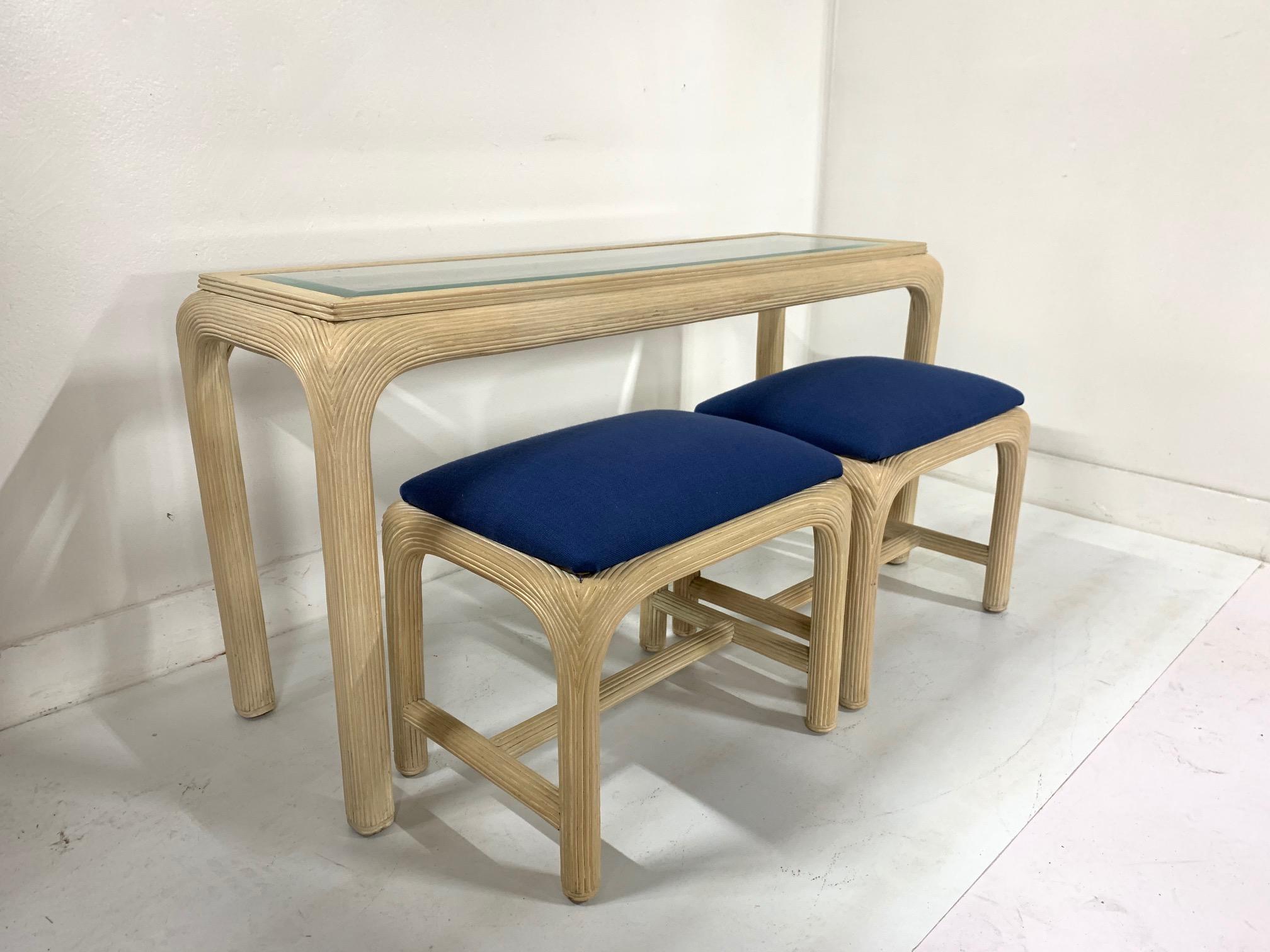 Modern console table with matching benches. The set has a reed frame, a glass beveled top, and matching blue upholstered benches.
Measures: Console: 54 W x 18 D x 28.5 H
Benches: 22.25 W x 16 D x 20 H.