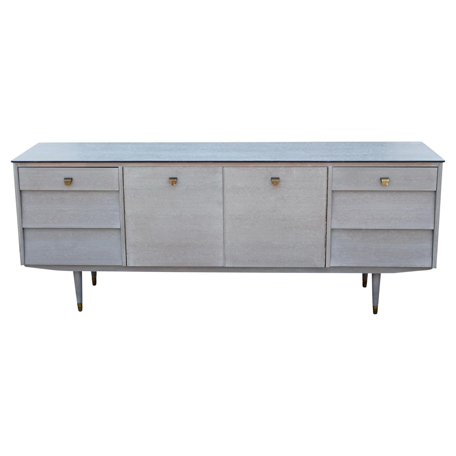 Wonderful modern custom sideboard or credenza. It has a newly cerused finish and brass handles. This credenza has six drawers and two cabinet doors with one interior shelf.
