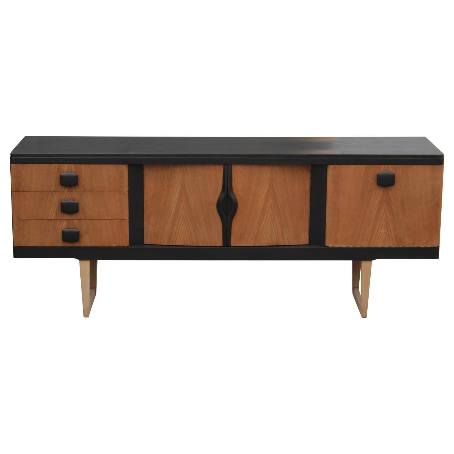Lovely restored modern credenza with a lovely two-tone finish. This piece features three drawers on the left and two cabinet spaces that open to reveal a single shelf.