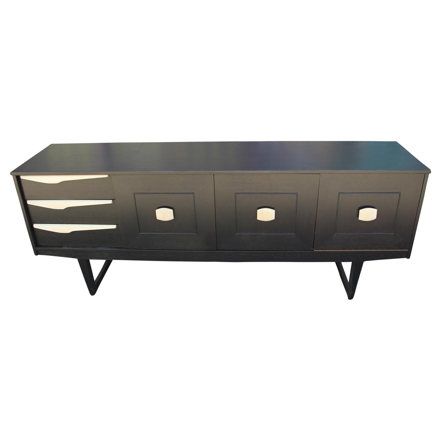 Wonderful modern custom sideboard or credenza newly restored with a black finish and wooden handles. This sideboard has three drawers, a larger middle cabinet, and another drop front cabinet with an interior shelf.