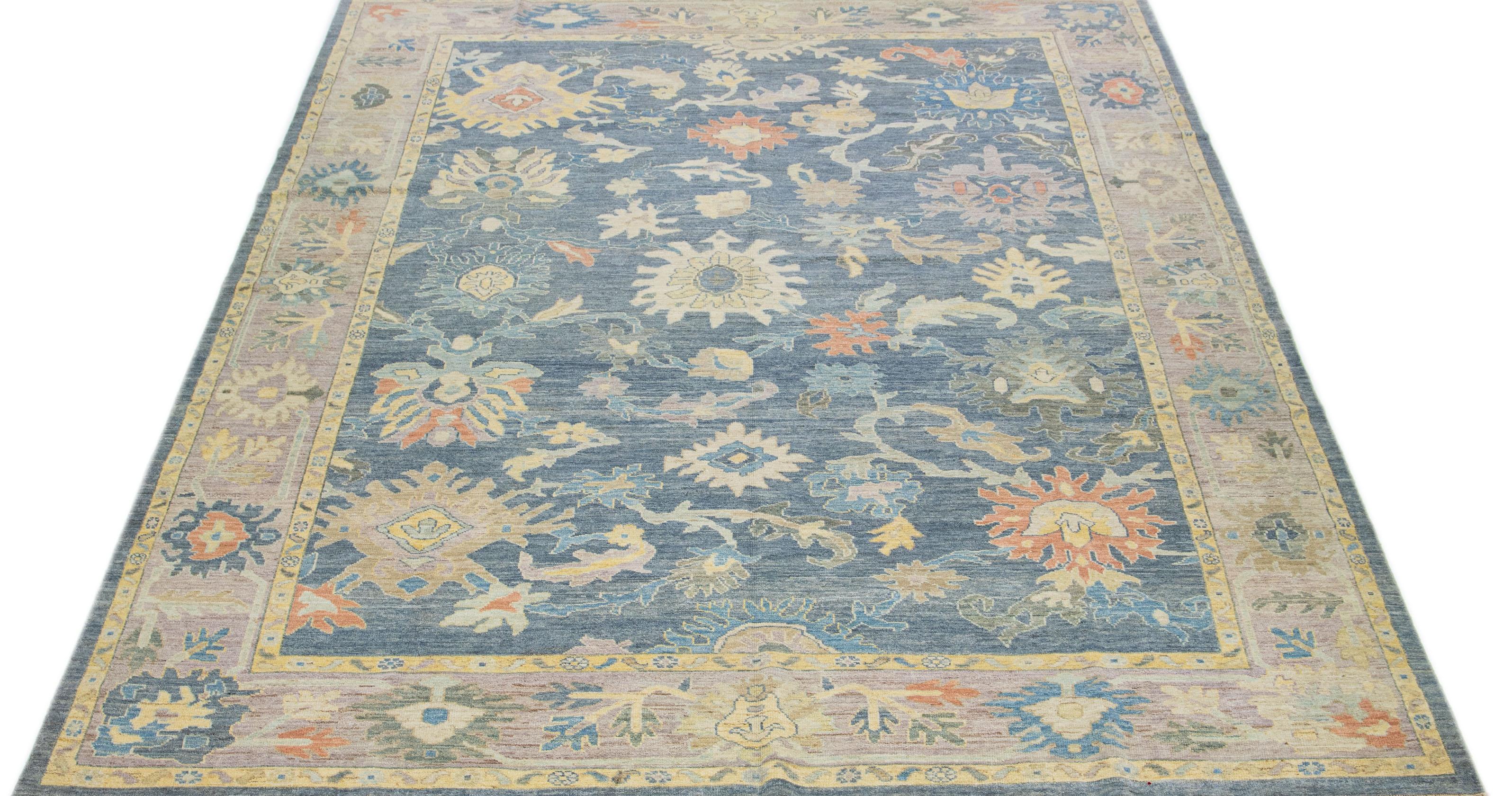 This contemporary take on the traditional Sultanabad style is showcased in an exquisite hand-knotted wool rug with a striking navy blue color. An intricately designed frame accentuates its all-over floral motif, adorned with multicolored accents