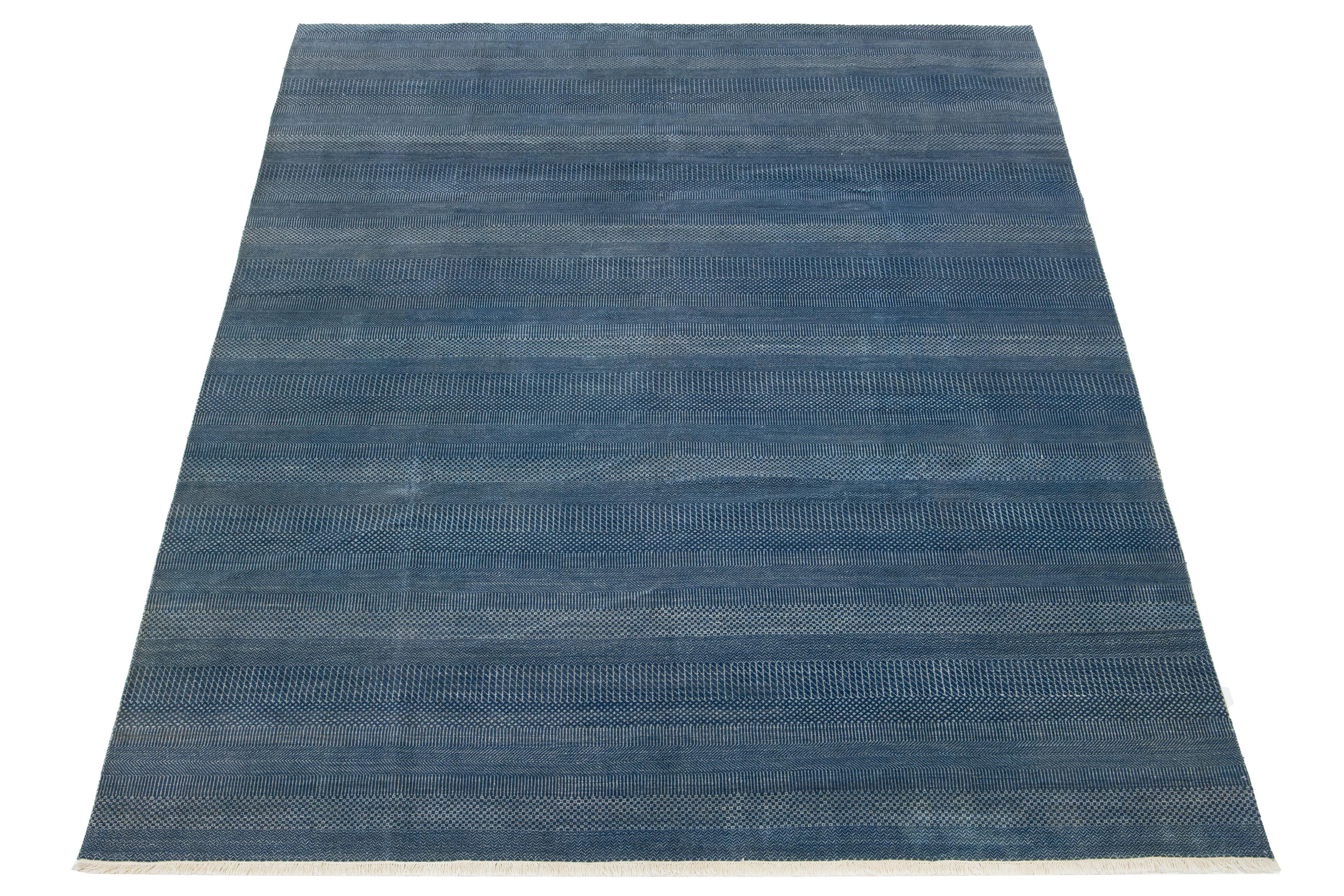 Dieser elegante, handgeknüpfte Wollteppich zeichnet sich durch ein modernes Design aus. Es zeigt ein sorgfältig gearbeitetes Feld in Blau, das mit komplizierten geometrischen Mustern verziert ist.

Dieser Teppich misst 9'2