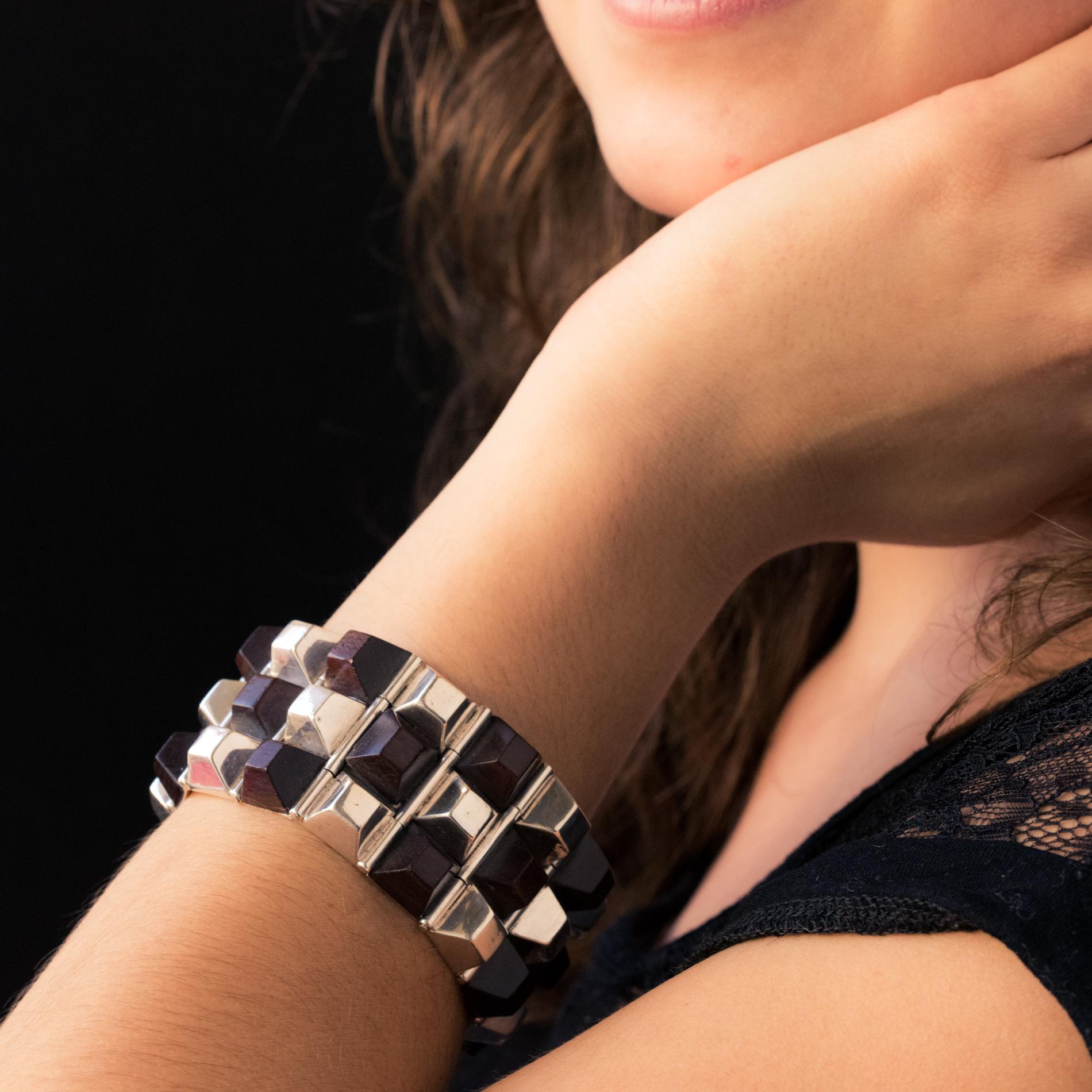 Bracelet in silver.
Geometric shaped, this incredible cuff bracelet is made up of rectangular patterns hinged together. Each is set on top of an alternation of silver and rosewood pyramids. The clasp is hinged with safety clip.
Length: 19.5 cm,