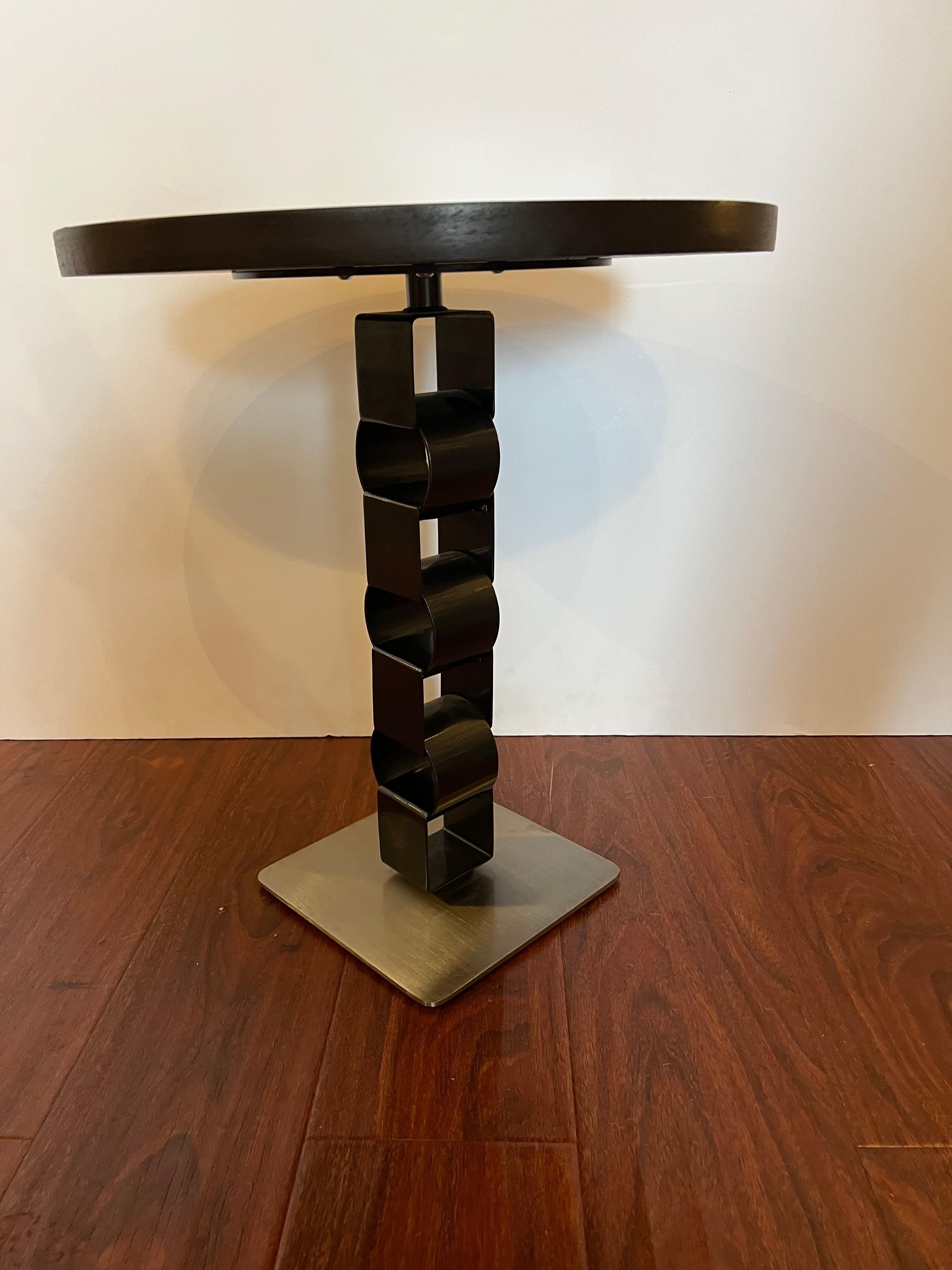 This modern round black gueridon is artfully designed with a combination of brush and lacquered steel. The graceful curves of its steel base flow together elegantly for a sophisticated look and a contemporary appeal. Its top is made of dark stained