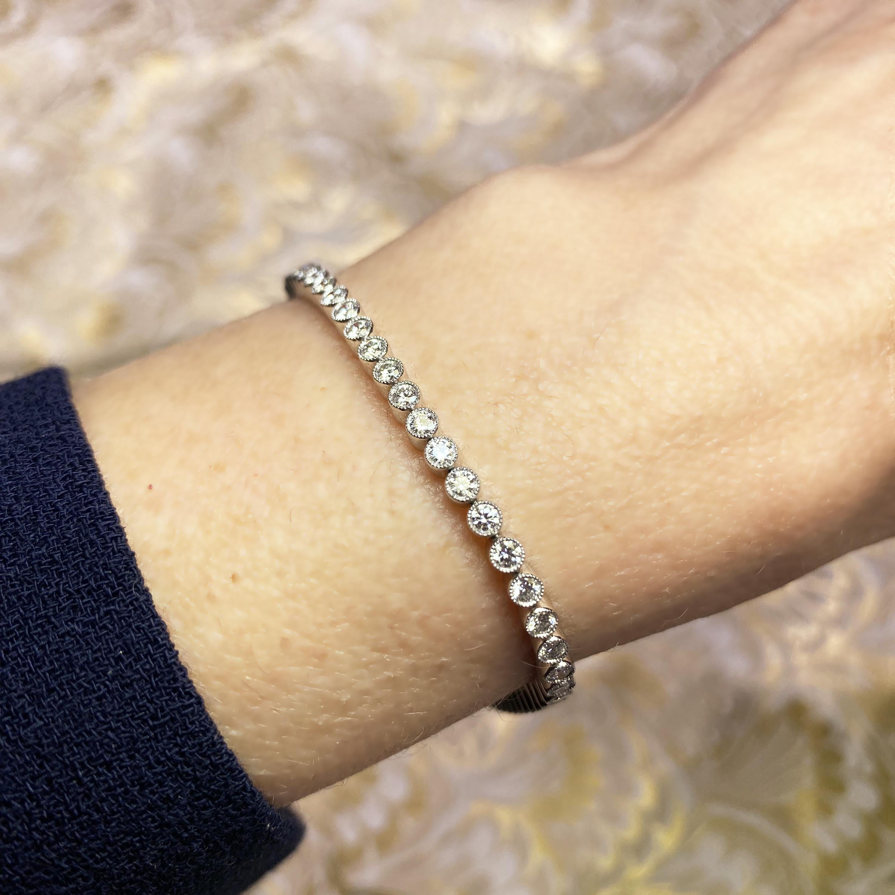 A modern diamond tennis bracelet set with round brilliant-cut diamonds, with a total weight of 2.83 carats, in millegrain edged rub over settings, individually hinged, with a box and tongue clasp, with safety catch, mounted in platinum.