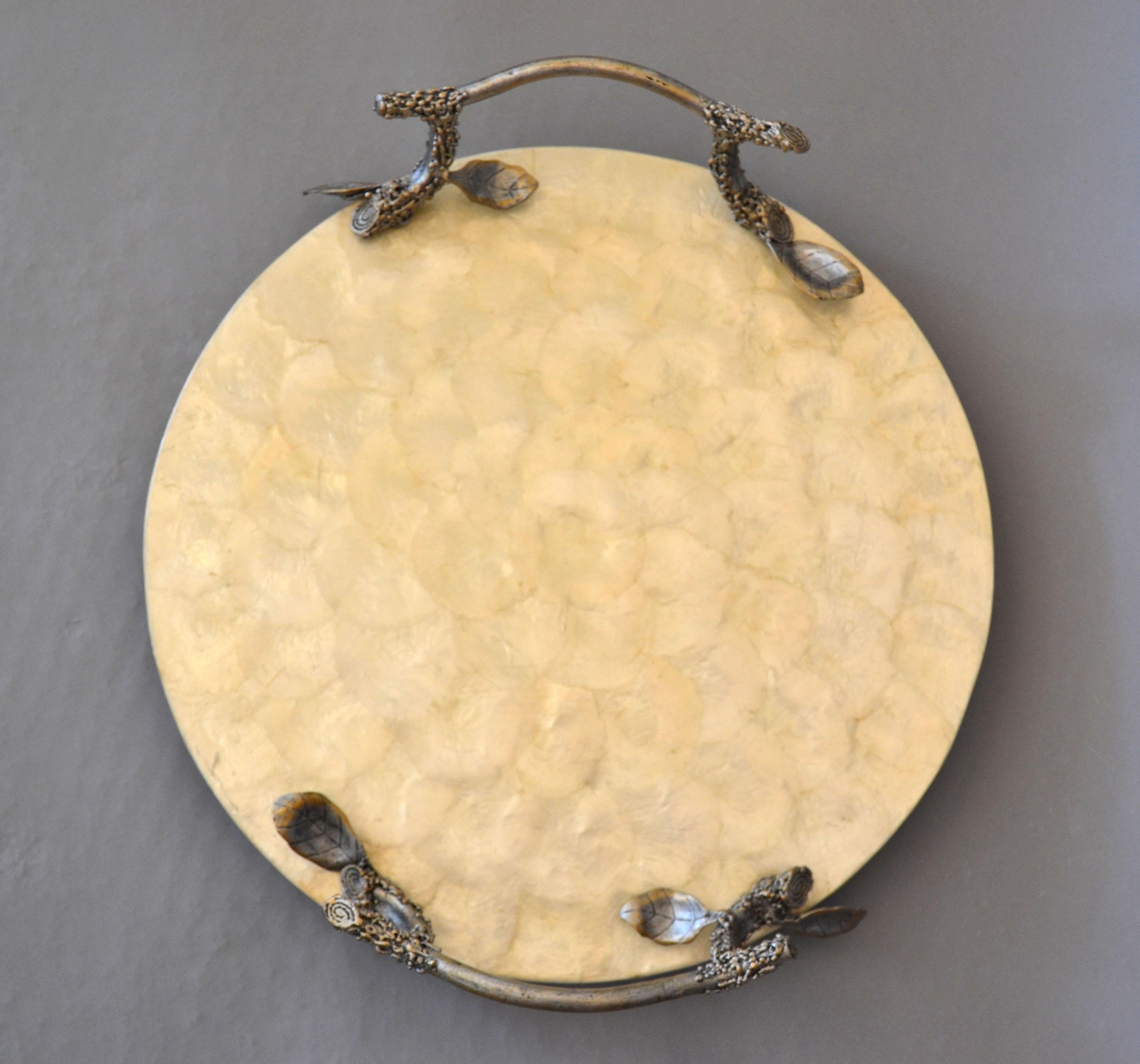 Charming round serving or decorative tray made out of capiz shells over pewter.
The handles are crafted as whimsical tree branches and it rests on 4 ball feet.
This tray is incredibly versatile, perfect for a serving platter, centerpiece or fruit