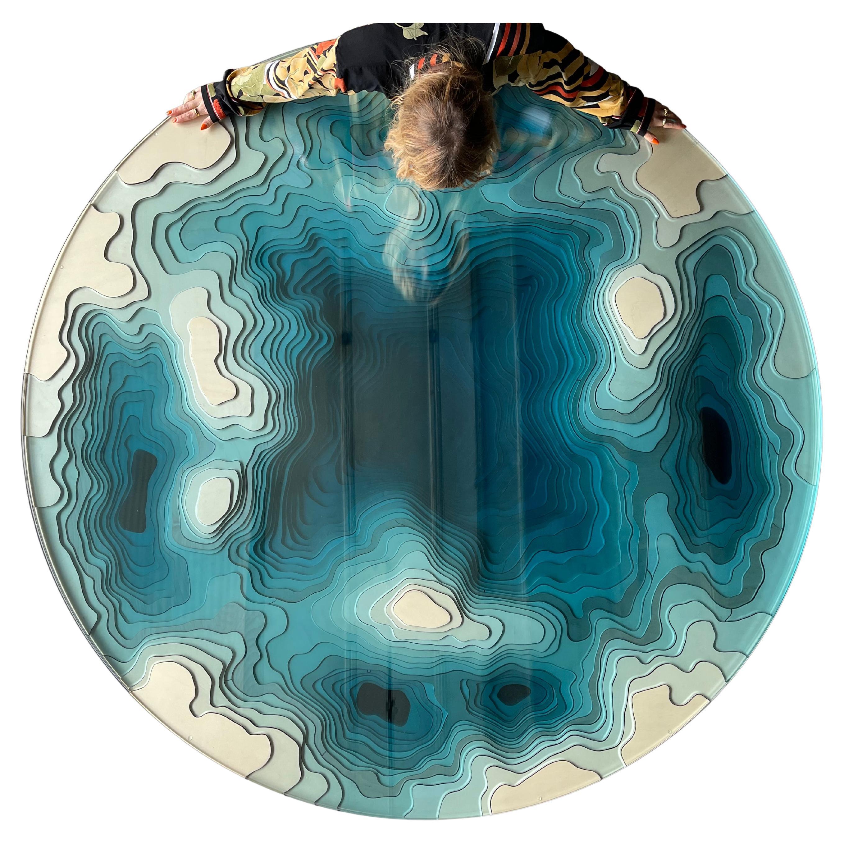 Abyss dining table expands Duffy’s explorations of the concept of depth with a mesmerising depiction of the Earth’s seabed, played out in vivid turquoise colours and grounded in a resplendent mirror polished stainless steel or matte black