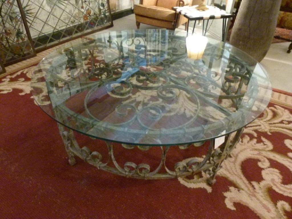 Round coffee table with a mixture of old and new. A 18th century iron base with a rounded glass on the top. 
The transparency of the glass allows to see the nice old piece below. A combination of antique and modern that creates balance and contrast