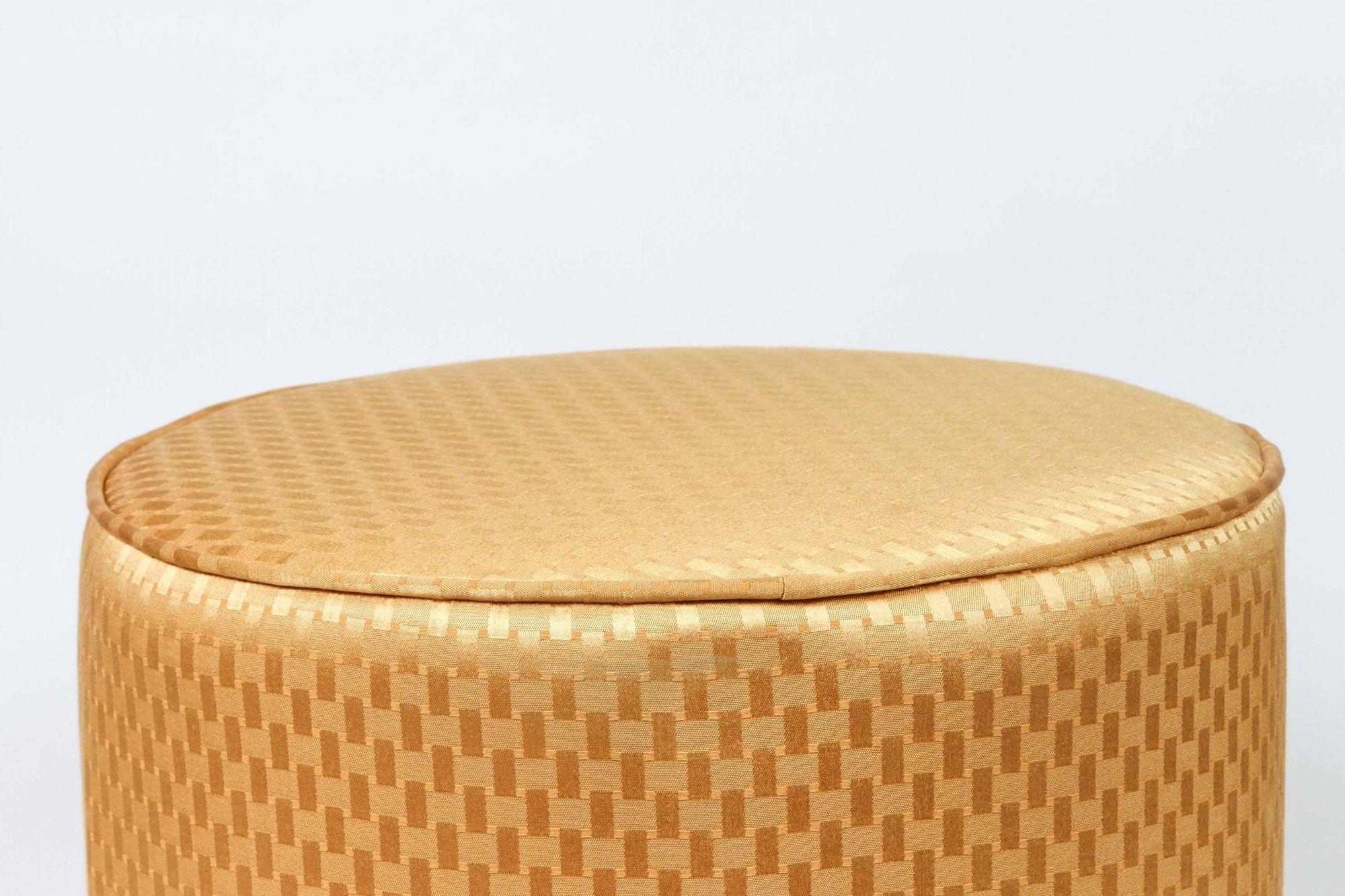Modern contemporary round Moroccan style stool in gold fabric upholstery in 1970s style.
Moroccan little pouf hassock, upholstered footstool or modern circular ottoman.
This versatile accent piece, pouf is designed primarily for seating but can be