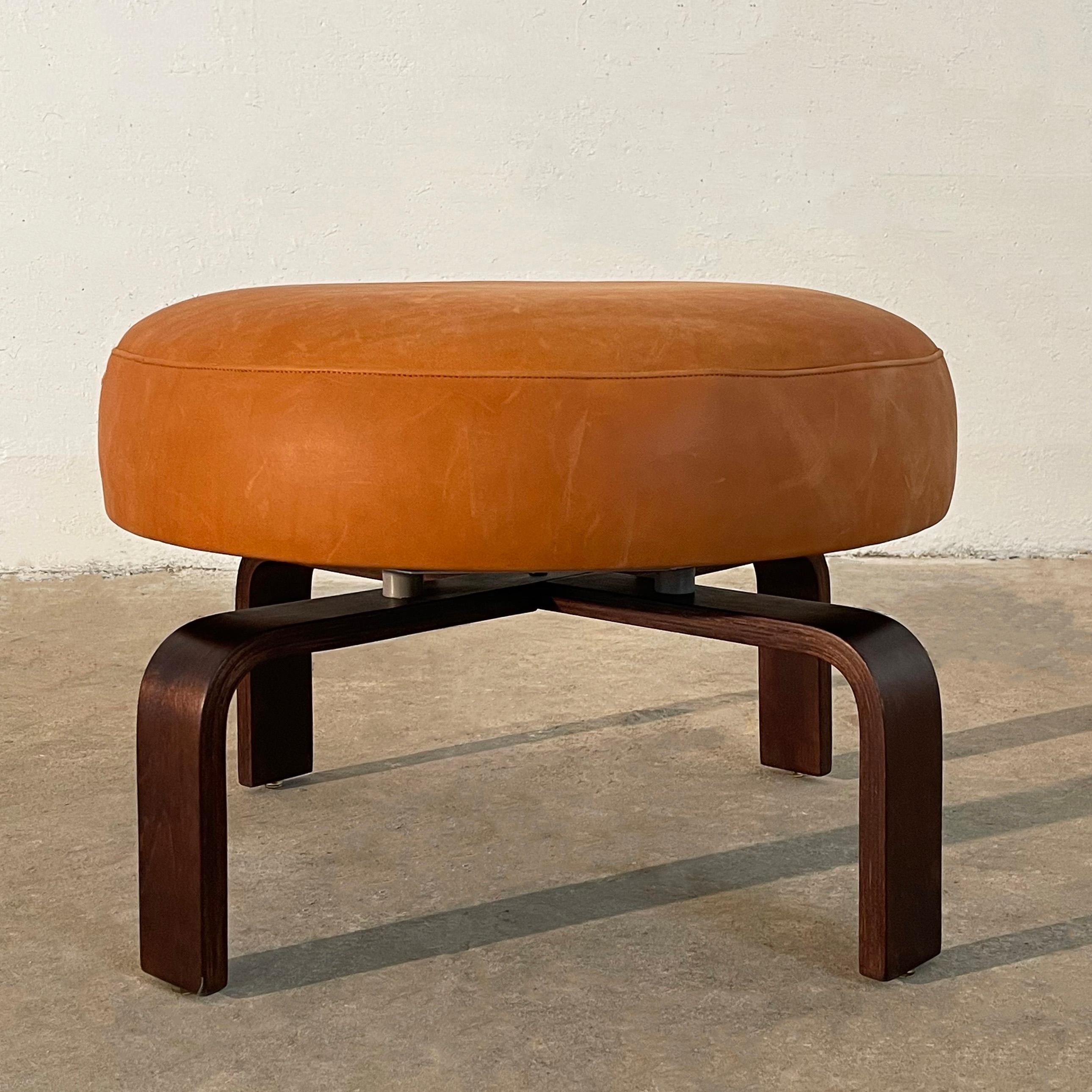 Modern, custom ottoman circa 1980's features a newly upholstered pouf in supple, rust orange leather that swivels on stained bent maple legs. Seat diameter is 24 inches and the footprint is 28 inches.


