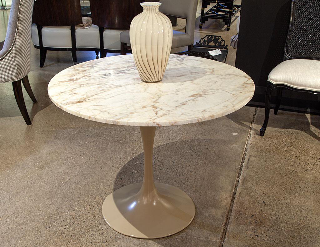 Modern round marble top table in the style of Eero Saarinen Pedestal table. Beautiful Italian marble with beige and rustic veining to create a stunning piece of stone. Resting upon a metal trumpet pedestal finished in a lacquered Taupe color. The