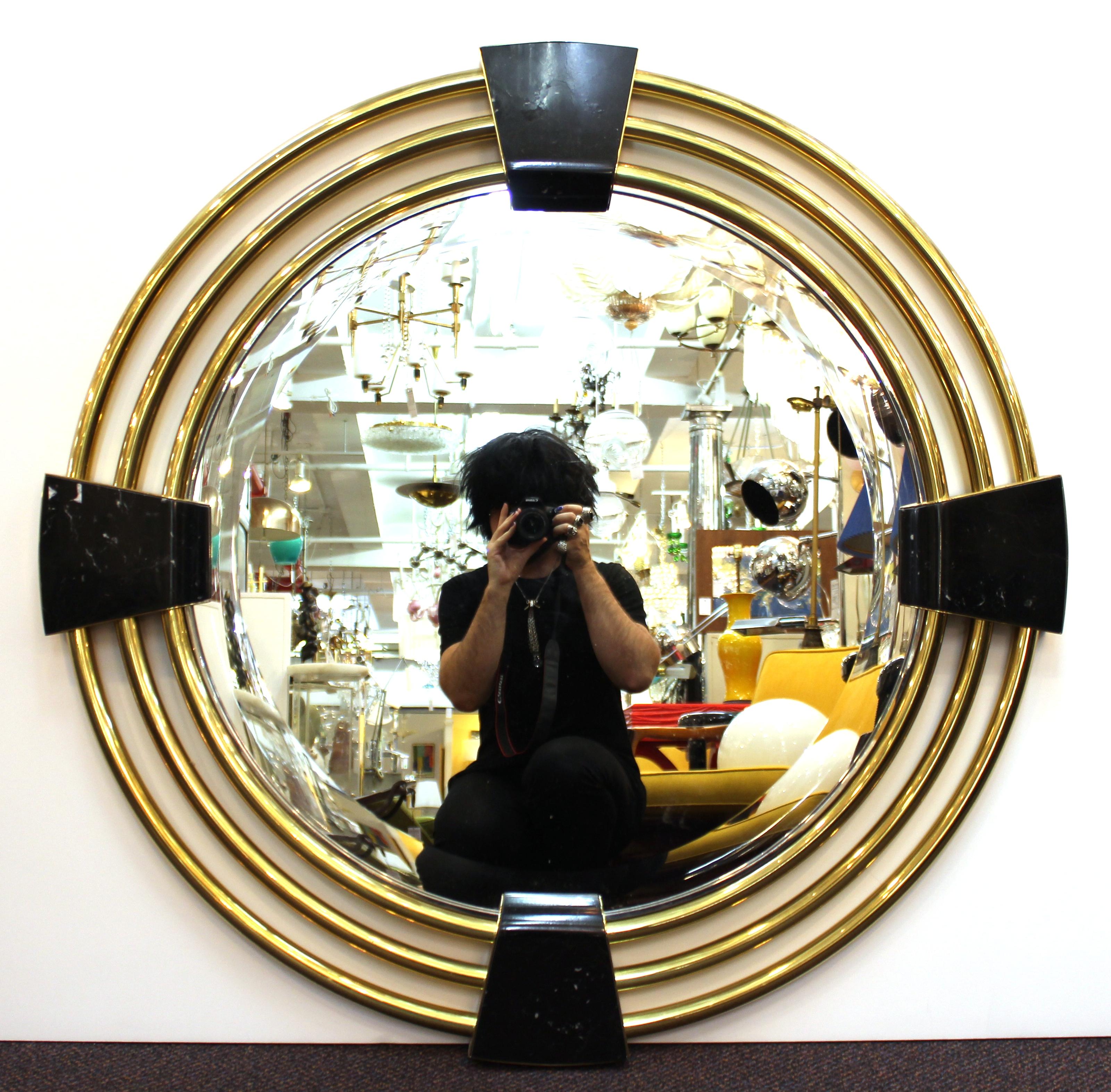 Modern round mirror, with concentric circular brass elements framing the mirror panel, held by four stone pieces. The piece is in great vintage condition with age-appropriate wear to the metal and stone surfaces.