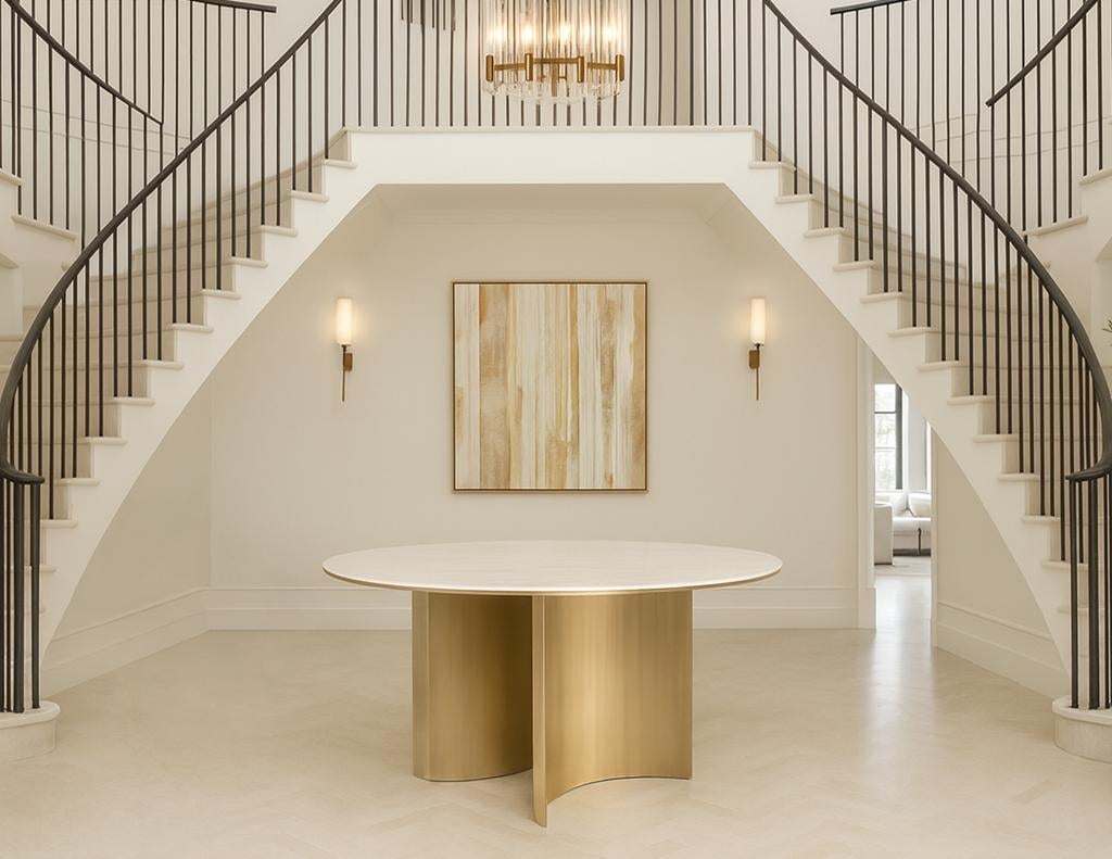 Questo tavolo da pranzo rotondo è caratterizzato da un piano in marmo travertino levigato con una morbida lucentezza opaca, incorniciato da un raffinato anello in ottone. La base scultorea presenta una coppia di piedistalli in metallo curvato in