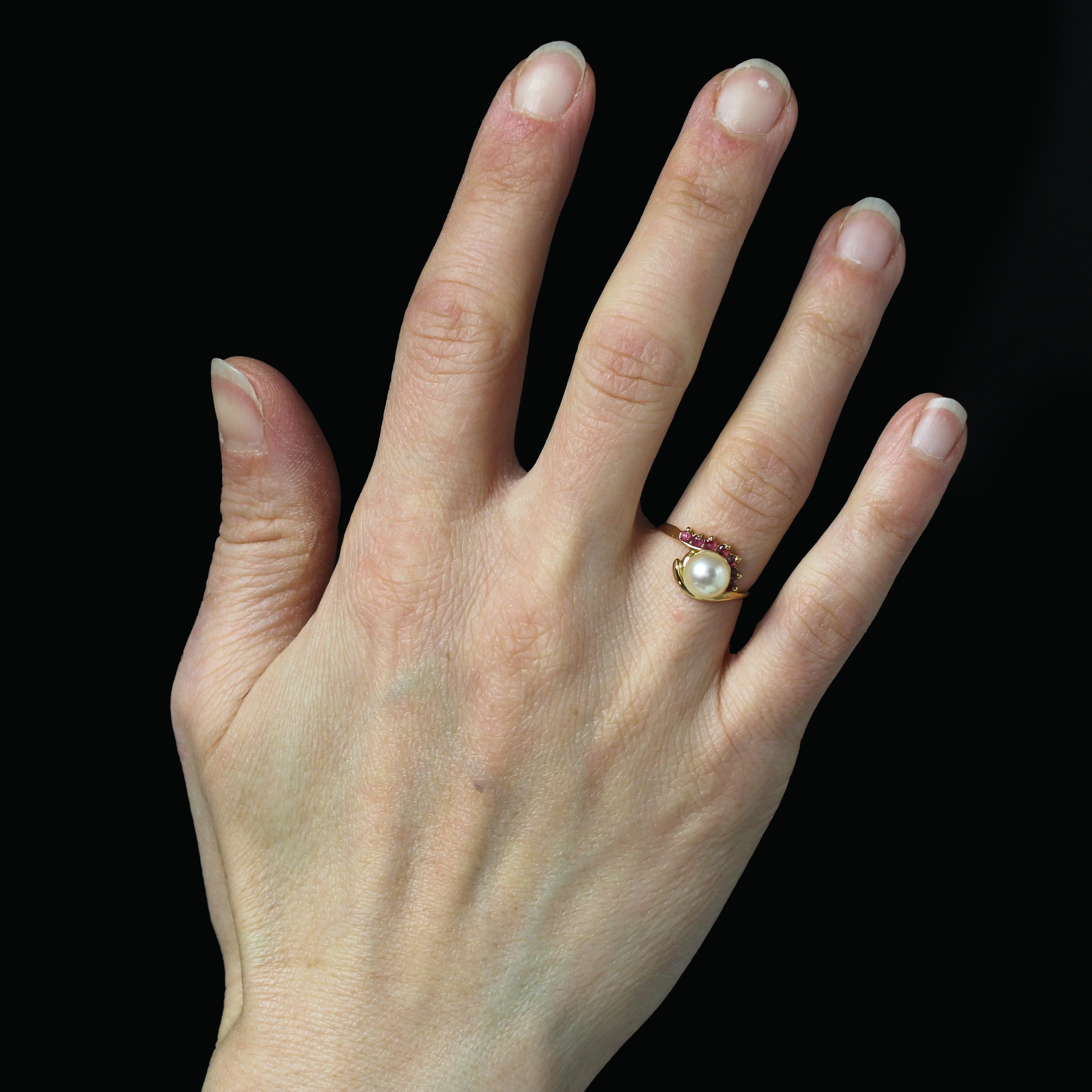 Ring in 18 karat yellow gold, eagle head hallmark.
Second hand gold ring, its setting forms a swirl on the front adorned with a line of seven small round rubies. A round pearly cream cultured pearl adorns the top of the ring.
Diameter of the pearl :