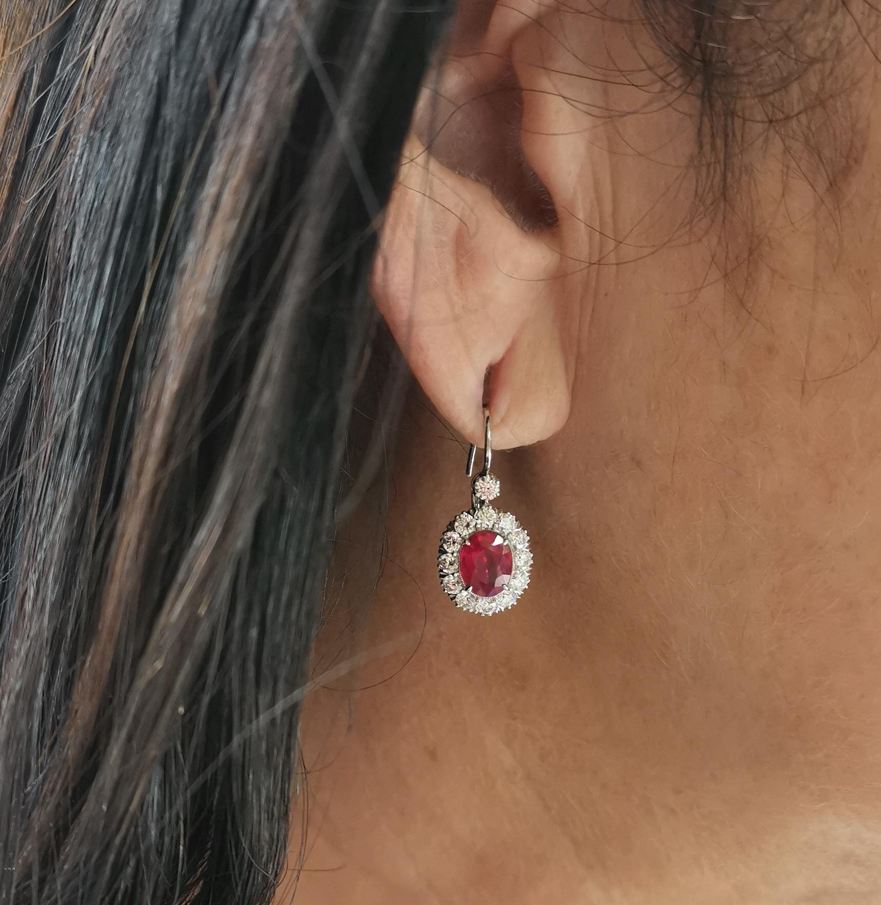 A pair of ruby and diamond cluster earrings, each set with an oval faceted ruby, with a total ruby weight of 2.50ct, surrounded by a cluster of round brilliant-cut diamonds and a single diamond above, with a total diamond weight of 1.23ct, mounted