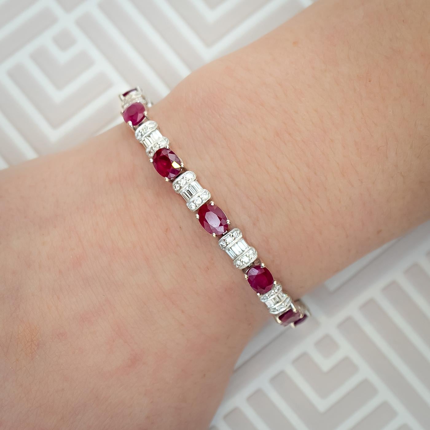 Ein modernes Rubin- und Diamantarmband, besetzt mit ovalen, facettierten Rubinen mit einem geschätzten Gesamtgewicht von 2,30 Karat, abwechselnd mit Diamantabschnitten, die jeweils mit drei Diamanten im Baguetteschliff besetzt sind, mit drei runden