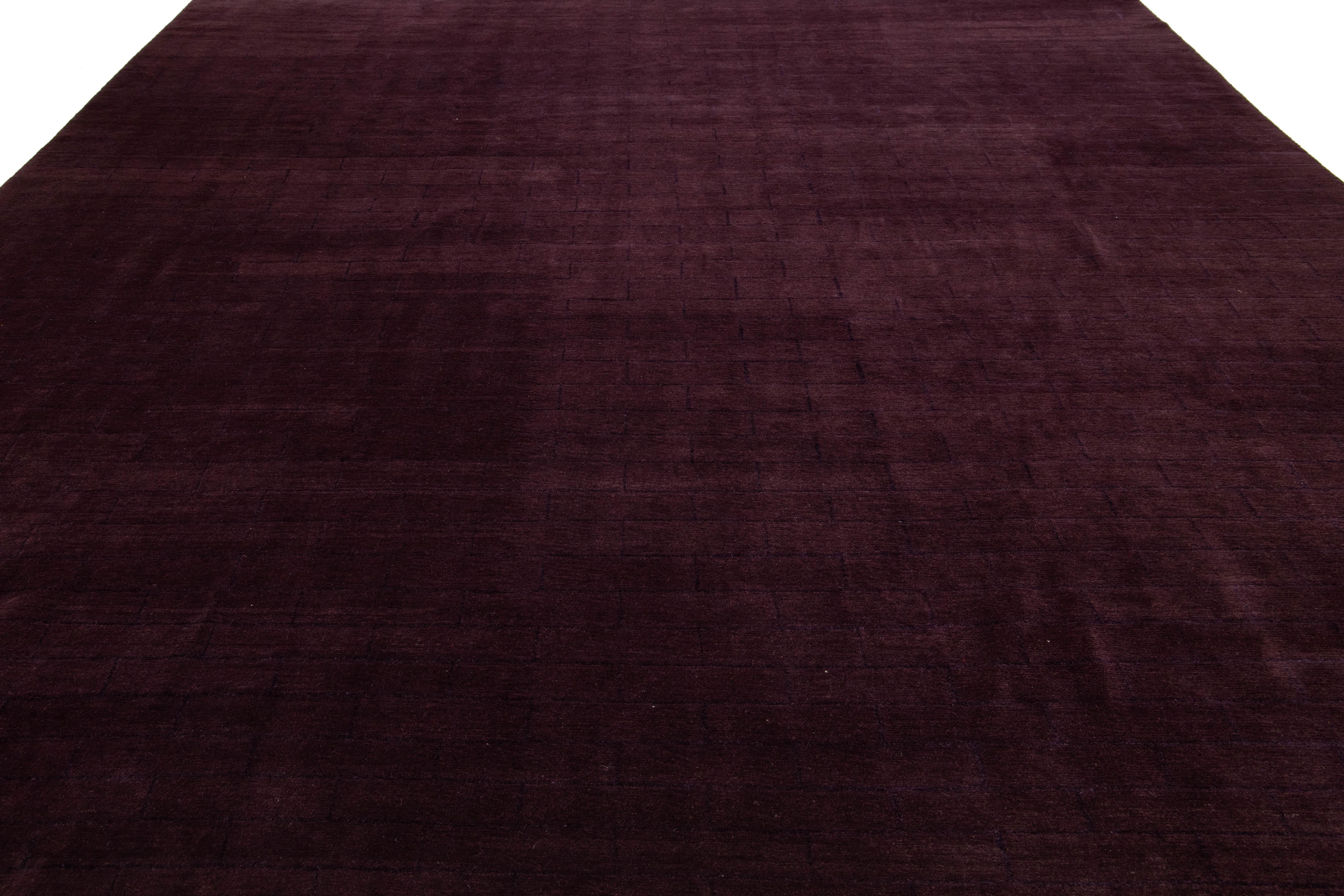 Ce tapis contemporain en tissage tibétain présente un motif rayé captivant dans des tons violets qui attire le regard. Fabriqué en laine ou en soie tibétaine de première qualité, il présente des détails complexes et un champ d'un bordeaux profond