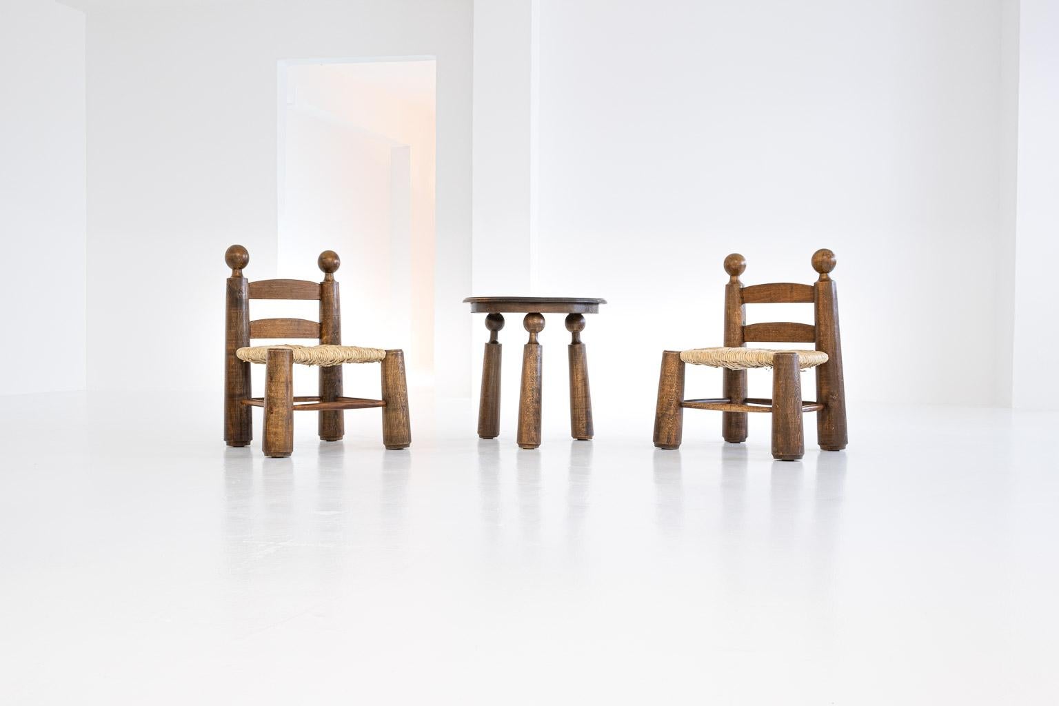 Set of two small chairs and a table by Charles Dudouyt, probably 1940s, solid oak, seats in rye straw, reupholstered after the original.

Measures: Chairs: height: 64 cm, seat height: 31 cm, width: 46 cm, depth: 43 cm
Table: height: 49 cm, diameter: